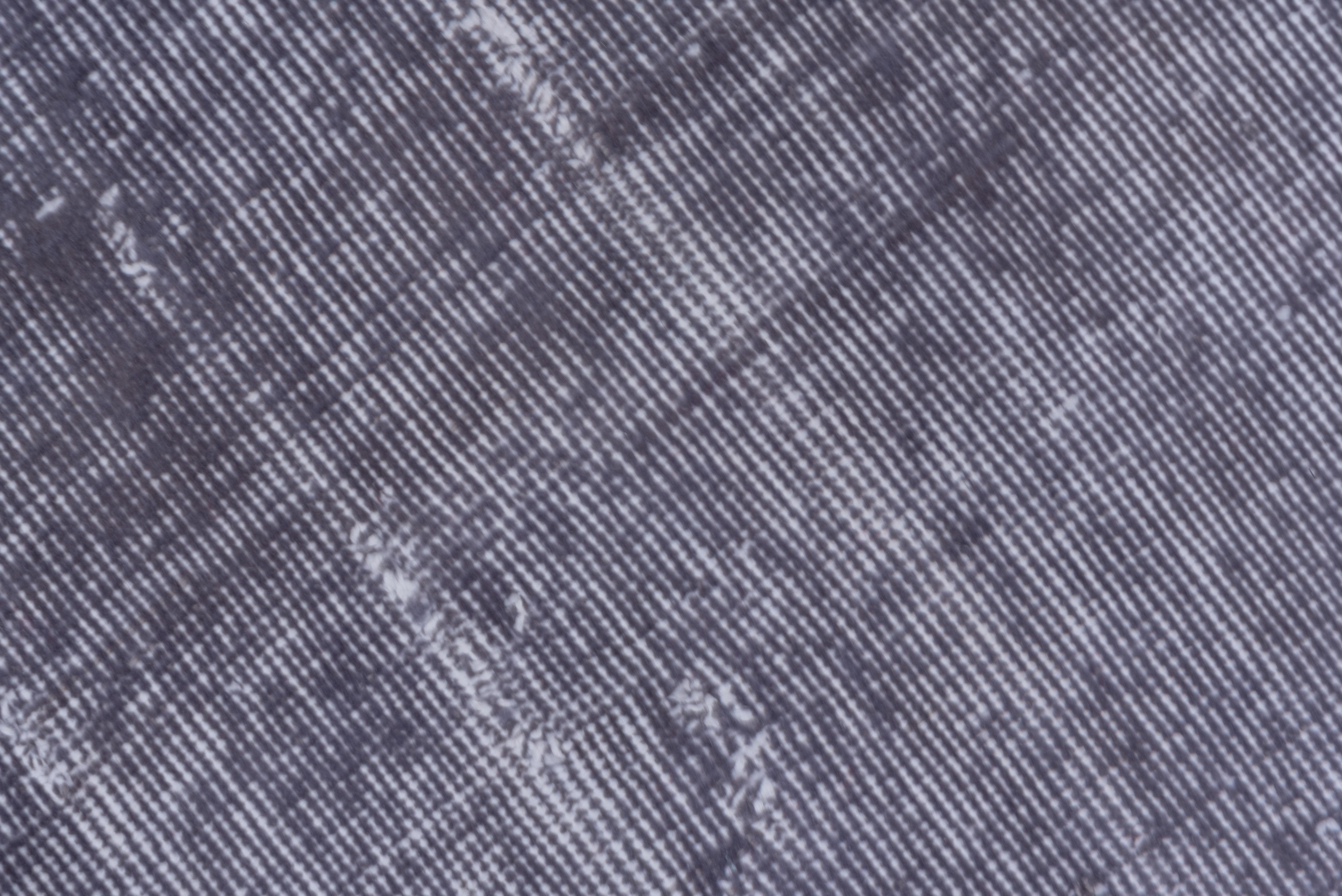 Ce tapis turc surteint gris sarcelle présente un motif défini par l'usure au-delà de la détresse générale. Des bandes verticales et horizontales de couleur blanc cassé se croisent près du centre. Le tapis n'a pratiquement pas de bordure.