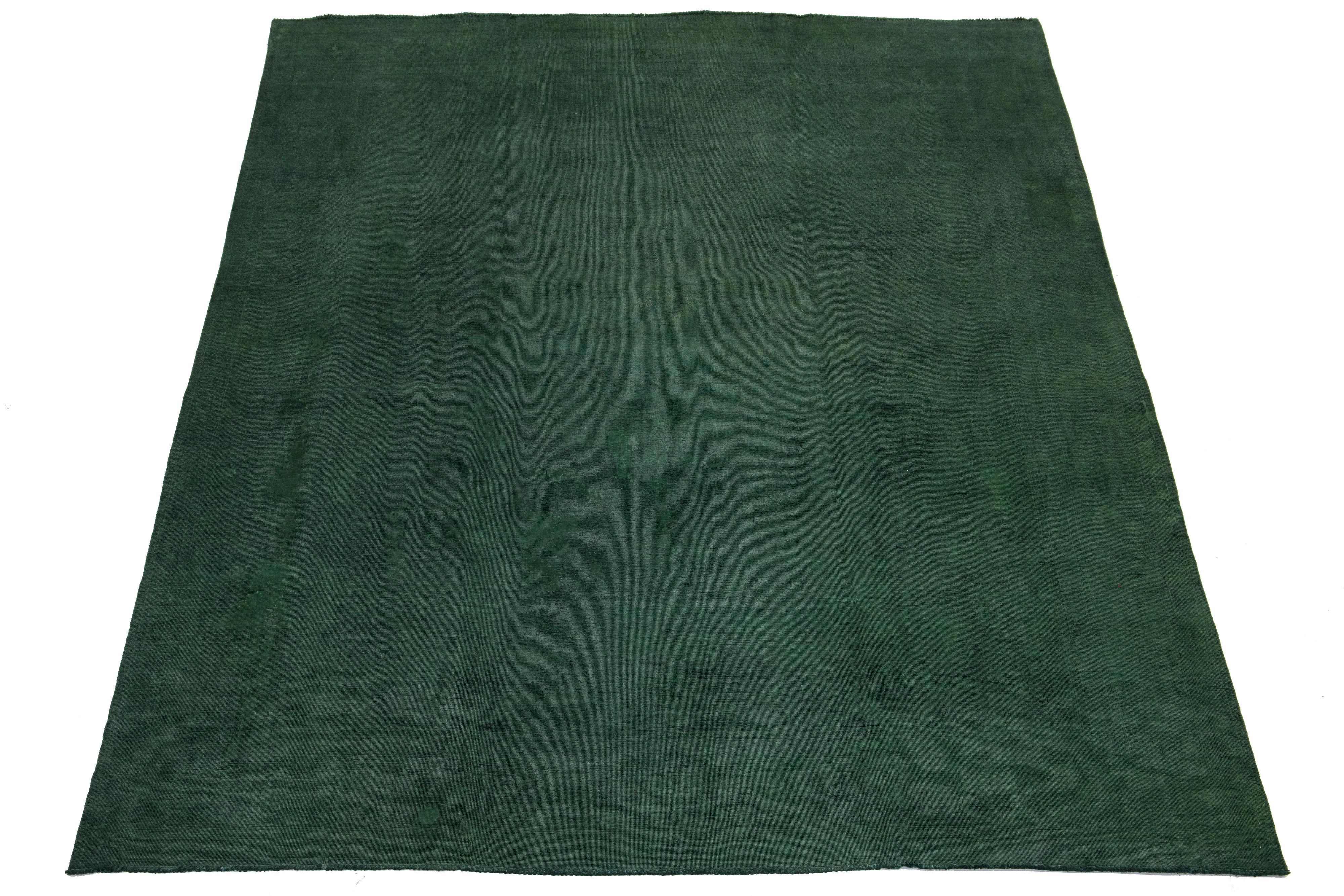 Questo tappeto persiano vintage in lana annodato a mano presenta un campo verde vibrante e un disegno floreale all-over con evidenti riflessi neri. Il motivo floreale sovratinto ne esalta il fascino, rendendolo una scelta ideale per elevare