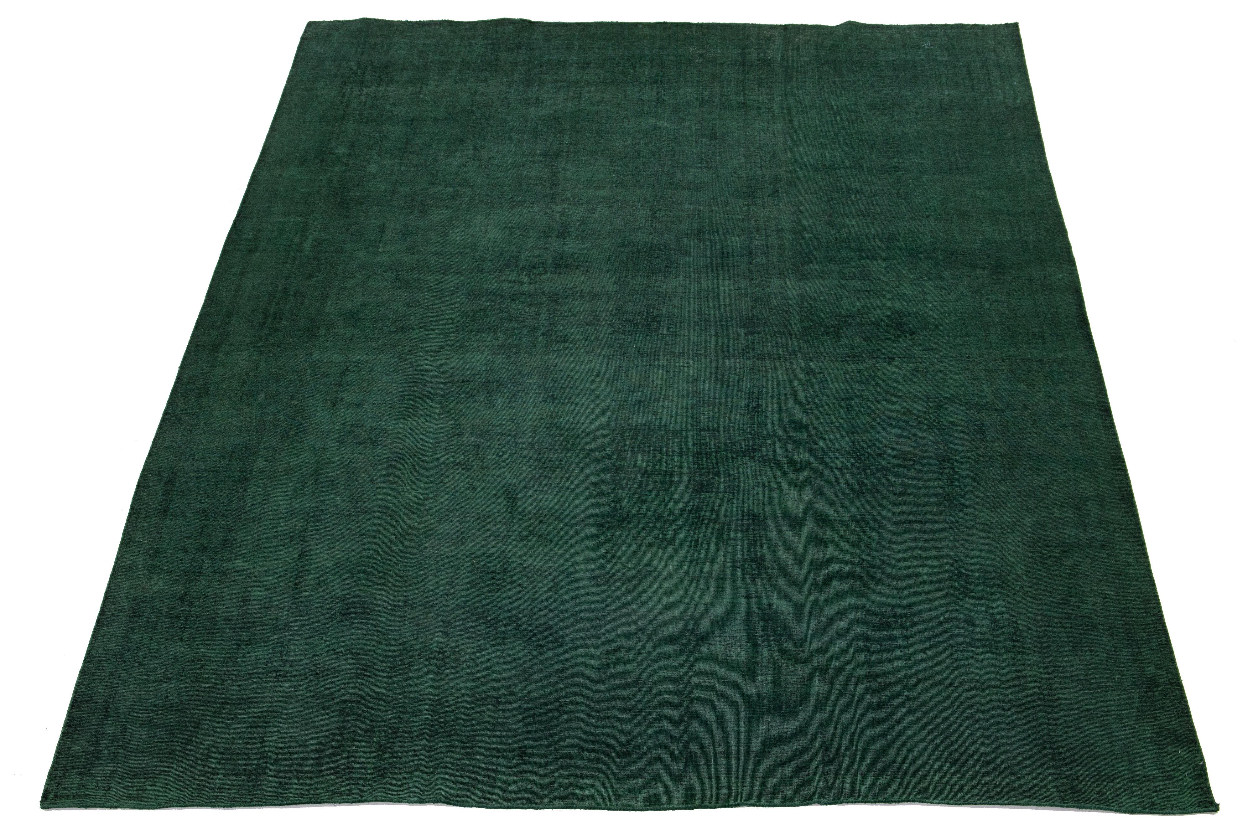 Cet exquis tapis persan vintage en laine nouée à la main présente un champ d'un vert éclatant. Il arbore un captivant design floral sur toute sa surface, élégamment mis en valeur par des accents noirs saisissants. Le motif médaillon magnifiquement