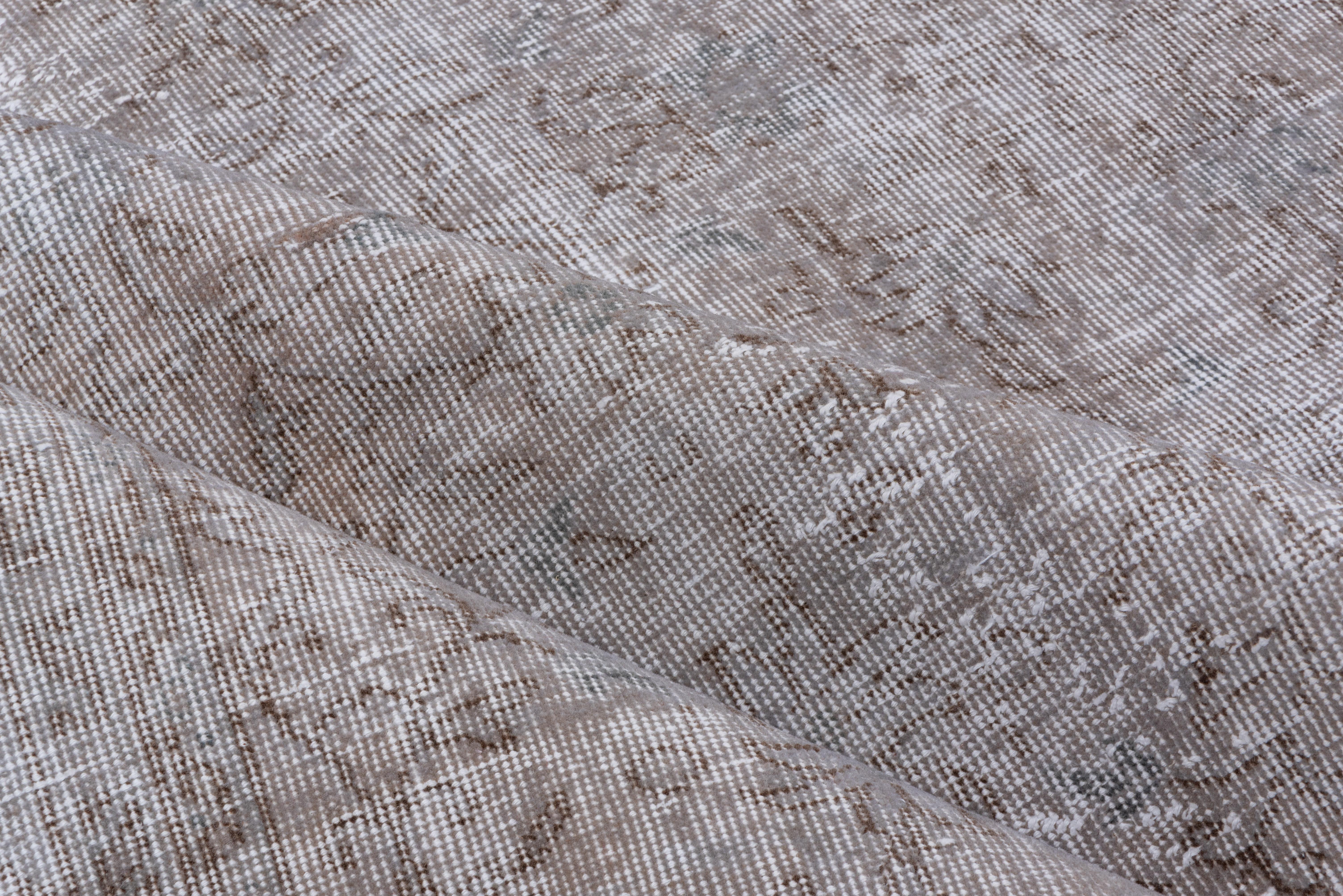 This light gray Turkish overdyed Sparta carpet has a pattern defined by the wear beyond the all-over general distress. Vertical and horizontal off white strips cross near the center. Shabby chic conditions and can offer some great texture for floor