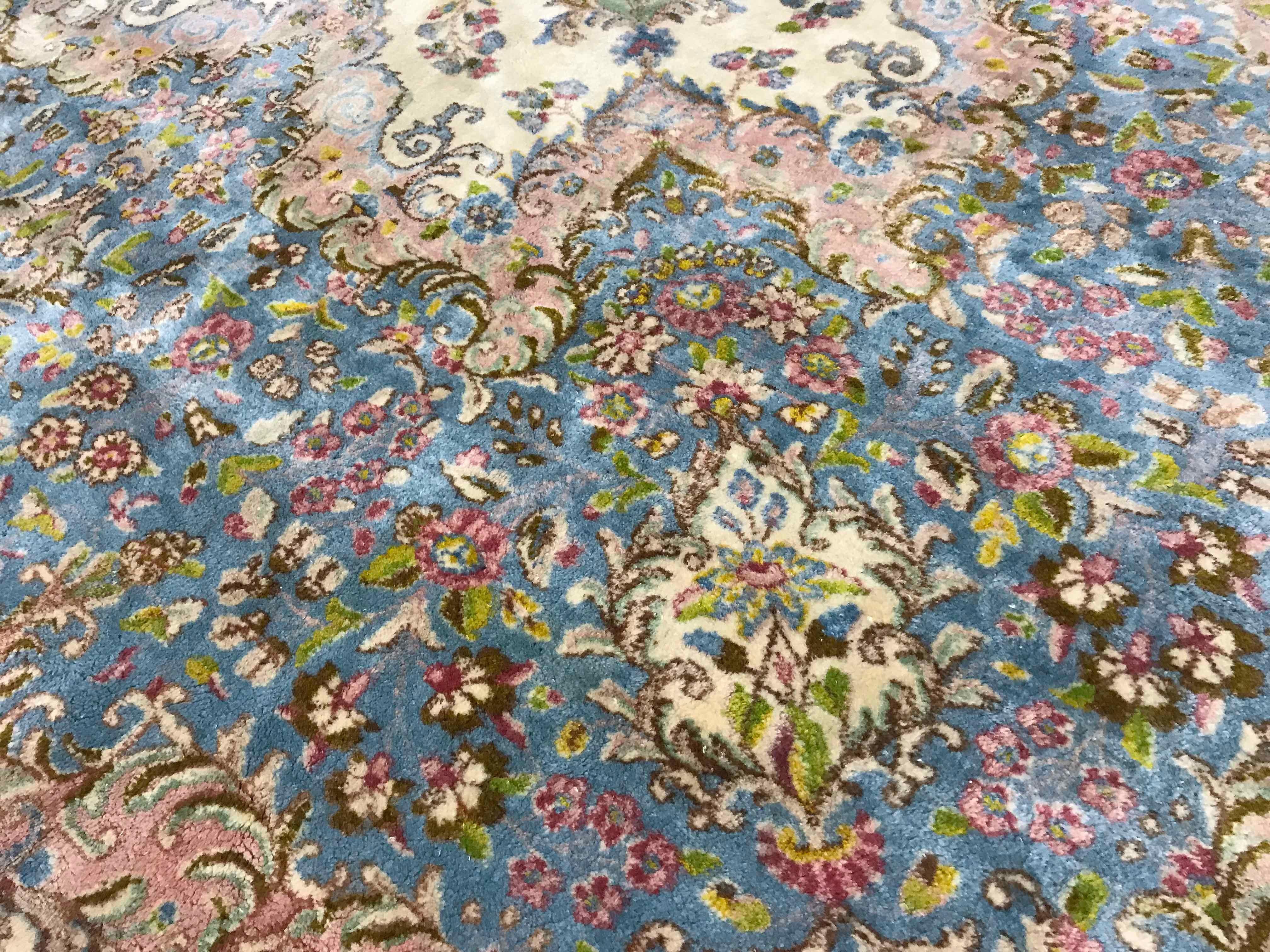 Übergroßer Vintage-Teppich aus Kerman, ca. 1940. Dieser attraktive, übergroße Kerman hat einen elfenbeinfarbenen Grund, der ein zentrales Blumenmuster in sanften Pastellblau- und Grüntönen umschließt. Die Hauptbordüre setzt die sanften Farben und