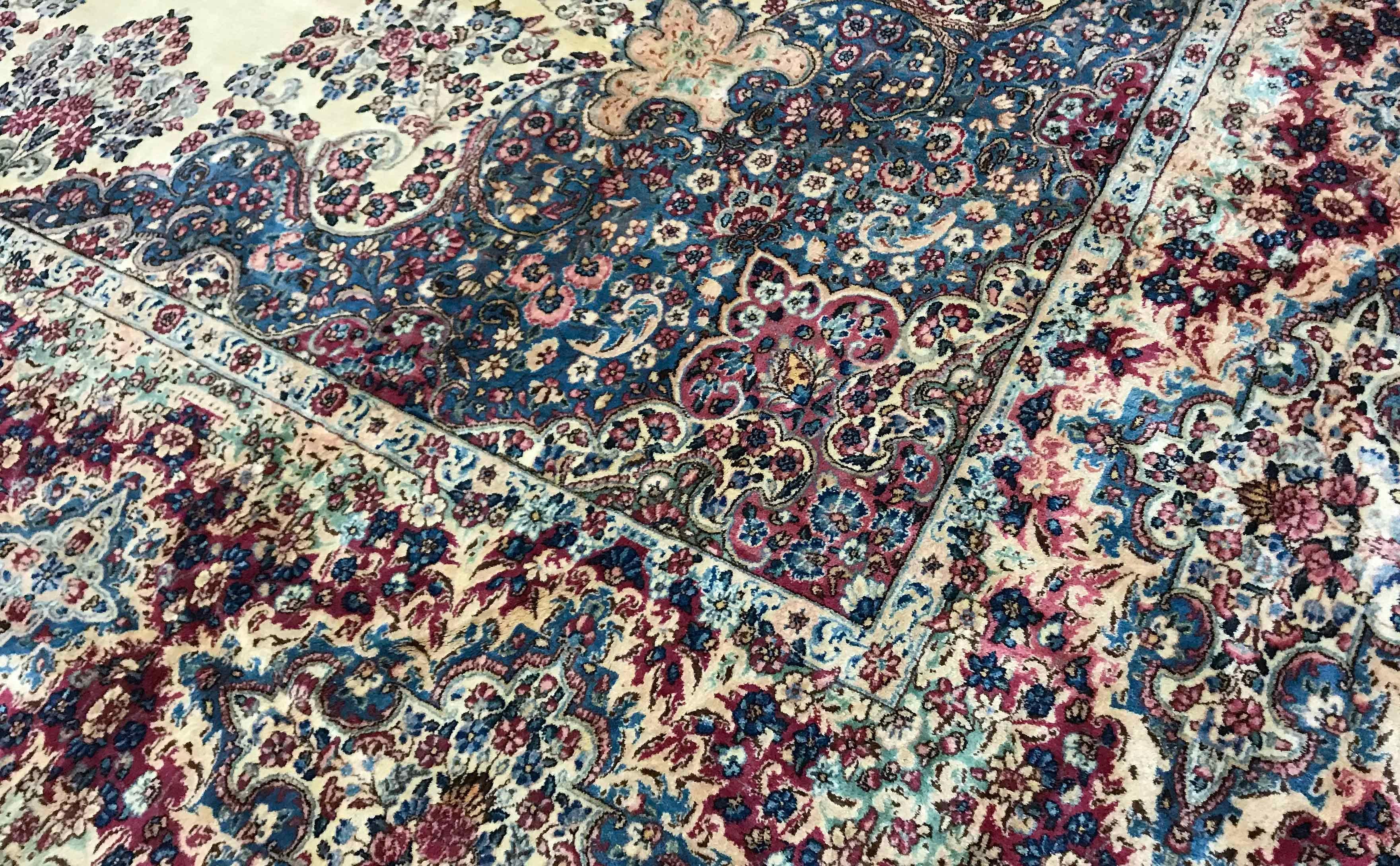 Alter persischer Kerman-Teppich, um 1940. Dieser große, überdimensionale Kerman-Teppich hat einen elfenbeinfarbenen Grund, der mit Blumen- und Rankenmustern gefüllt ist, die ein kleines zentrales Medaillon umschließen. Die umgebende Bordüre