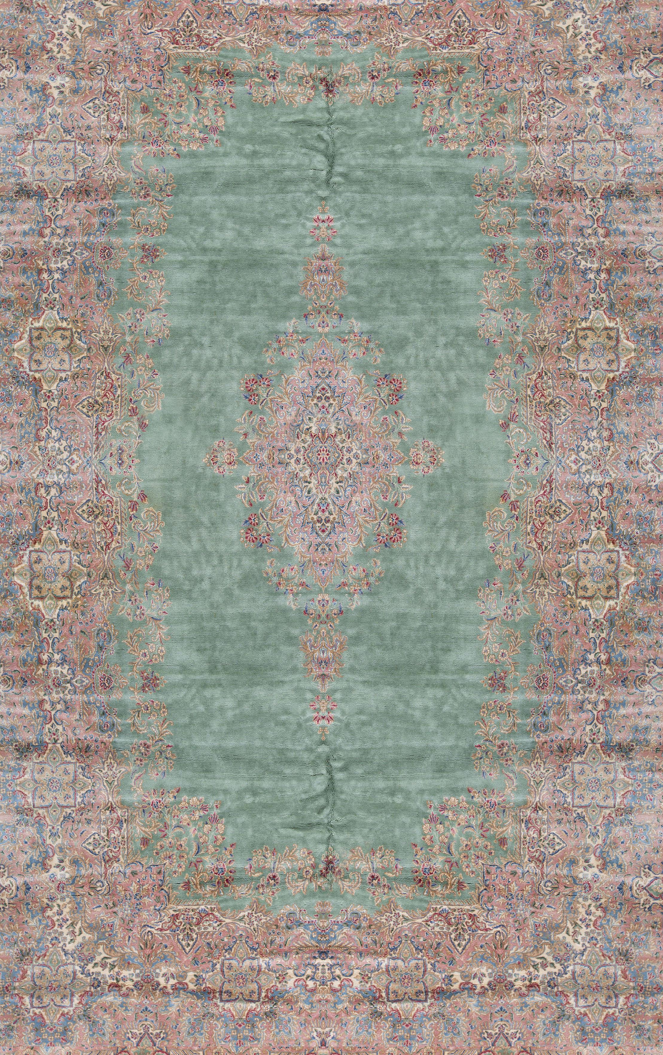 Vintage Persian Kerman rug, circa 1940. A wonderful composition to this rug with the soft green field both enclosing and surrounded by floral designs in soft gentle rose and blues to create this large oversized rug with a gentle style and look.