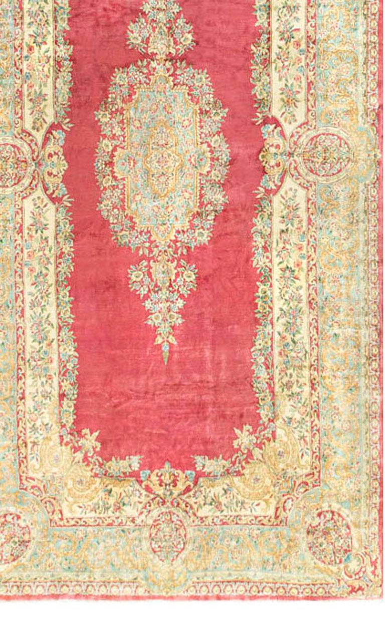 Vintage Persian Kirman rug, circa 1930. This glorious rug with its unusual length and width will creates a dramatic entrance to any room setting. The soft rose field encloses a central medallion filled with floral motifs which are repeated in the