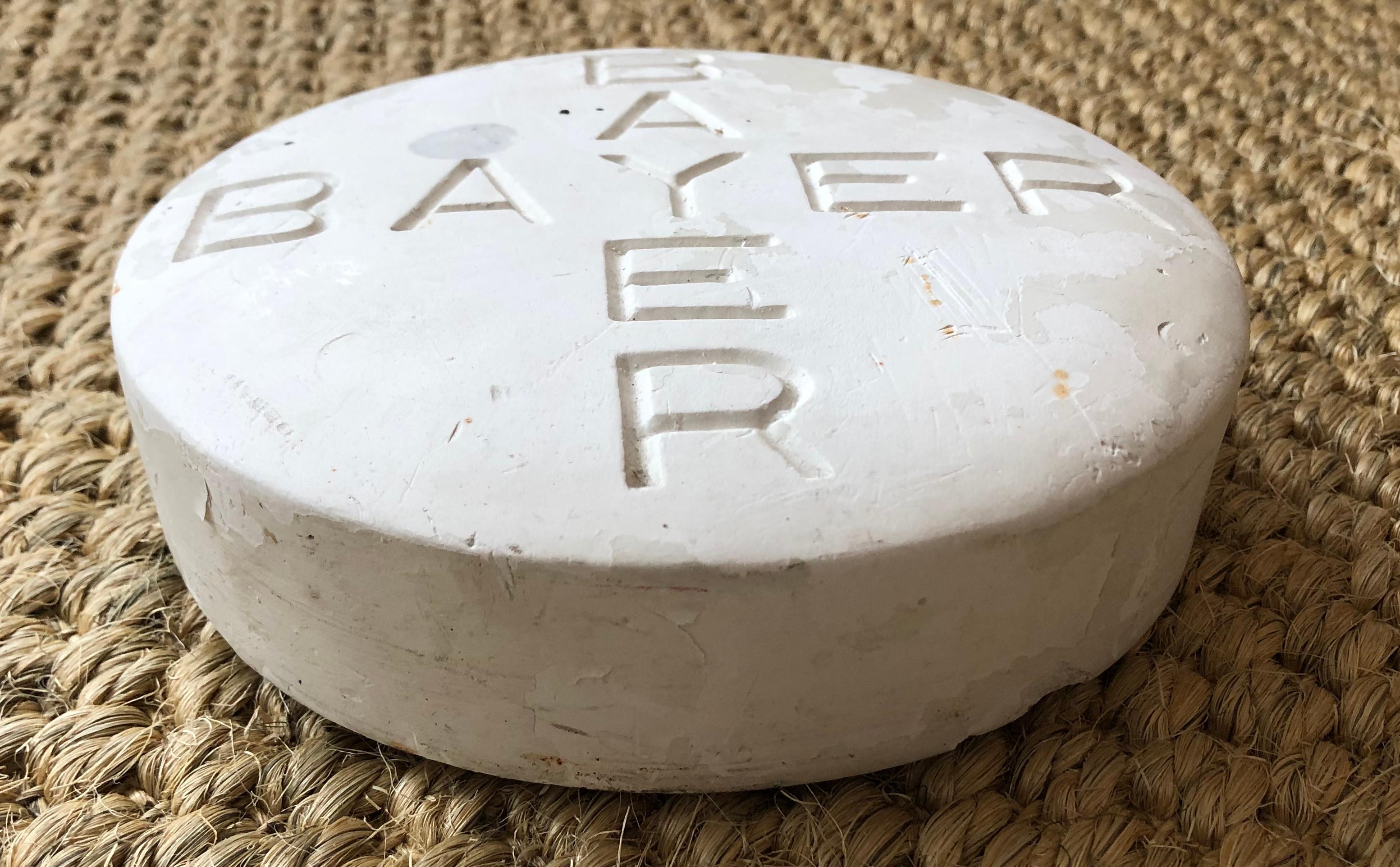 An oversized Bayer aspirin pill in plaster, created as an advertising promotional novelty for a pharmacy. 
Diameter: 7 inches.
   