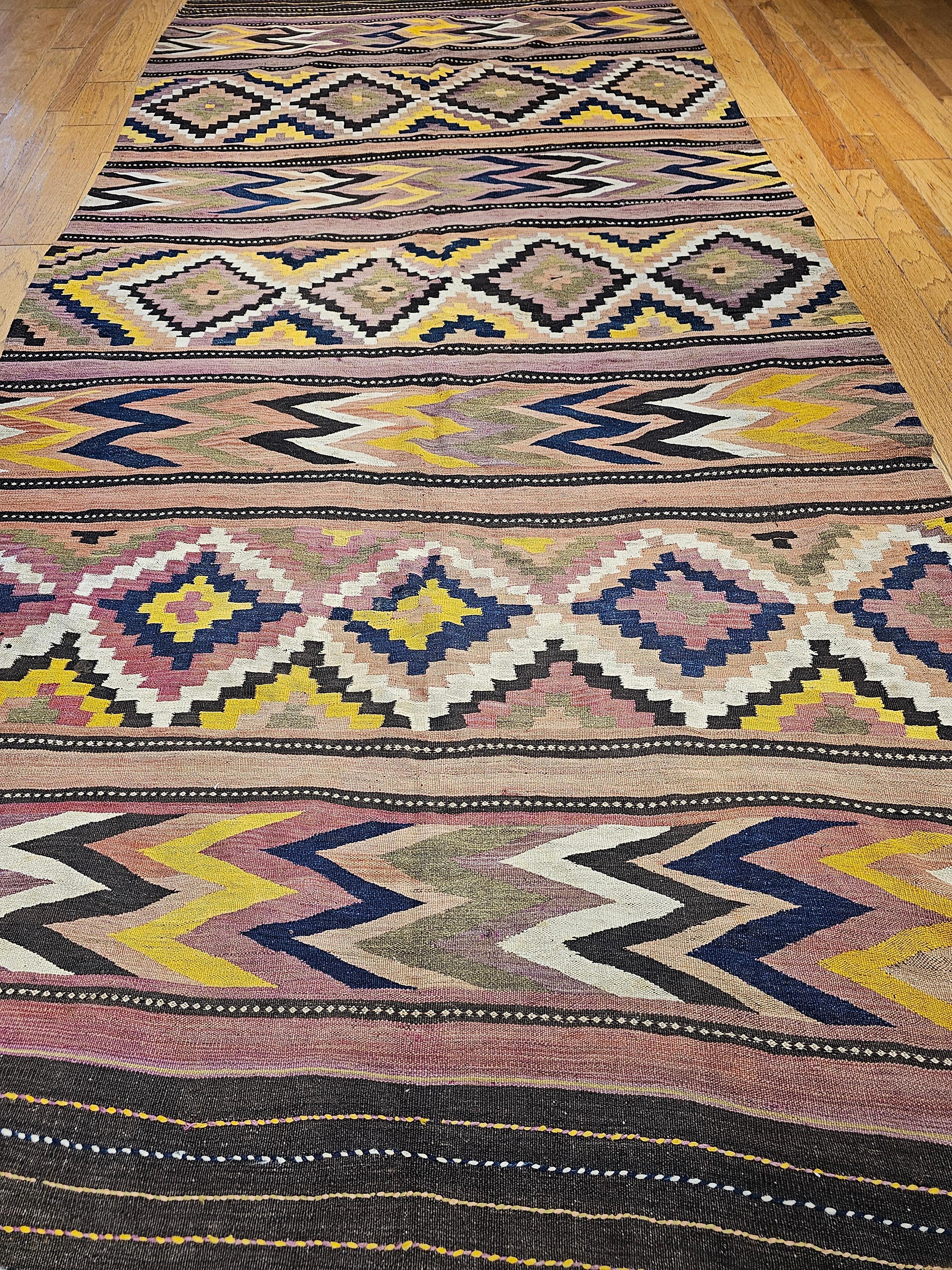 An oversized vintage Moroccan kilim “gallery/corridor” rug from the mid 1900s.  Beautiful geometric designs with wonderful colors in green, purple, yellow, brown, blue, and other shades.   The size of the rug makes it ideal either as a gallery or