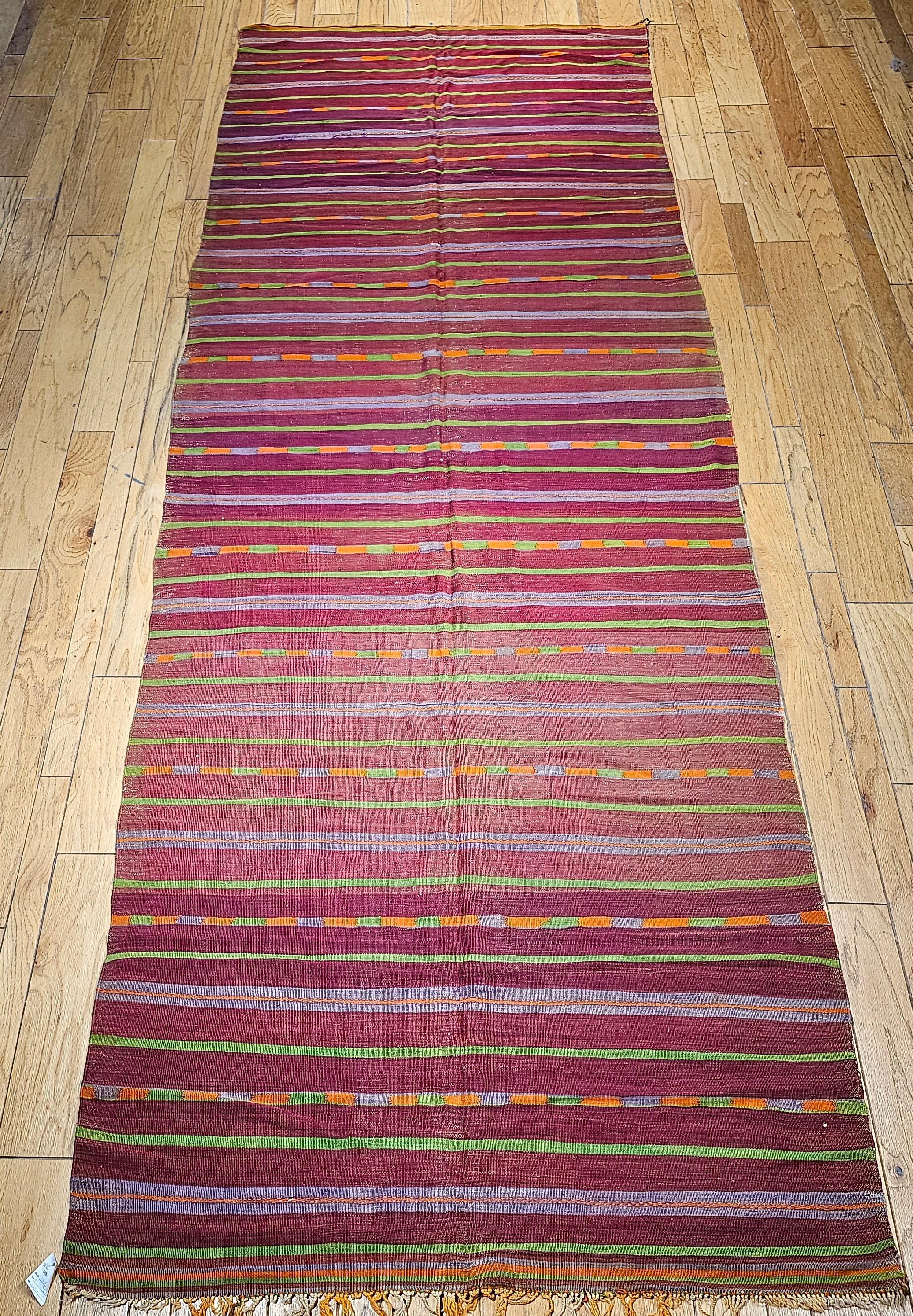 Magnifique tapis kilim marocain vintage du milieu des années 1900 avec un beau motif de rayures et de merveilleuses couleurs douces en rouge, vert, violet, jaune, lavande et autres nuances.   La taille du tapis en fait un objet idéal pour les