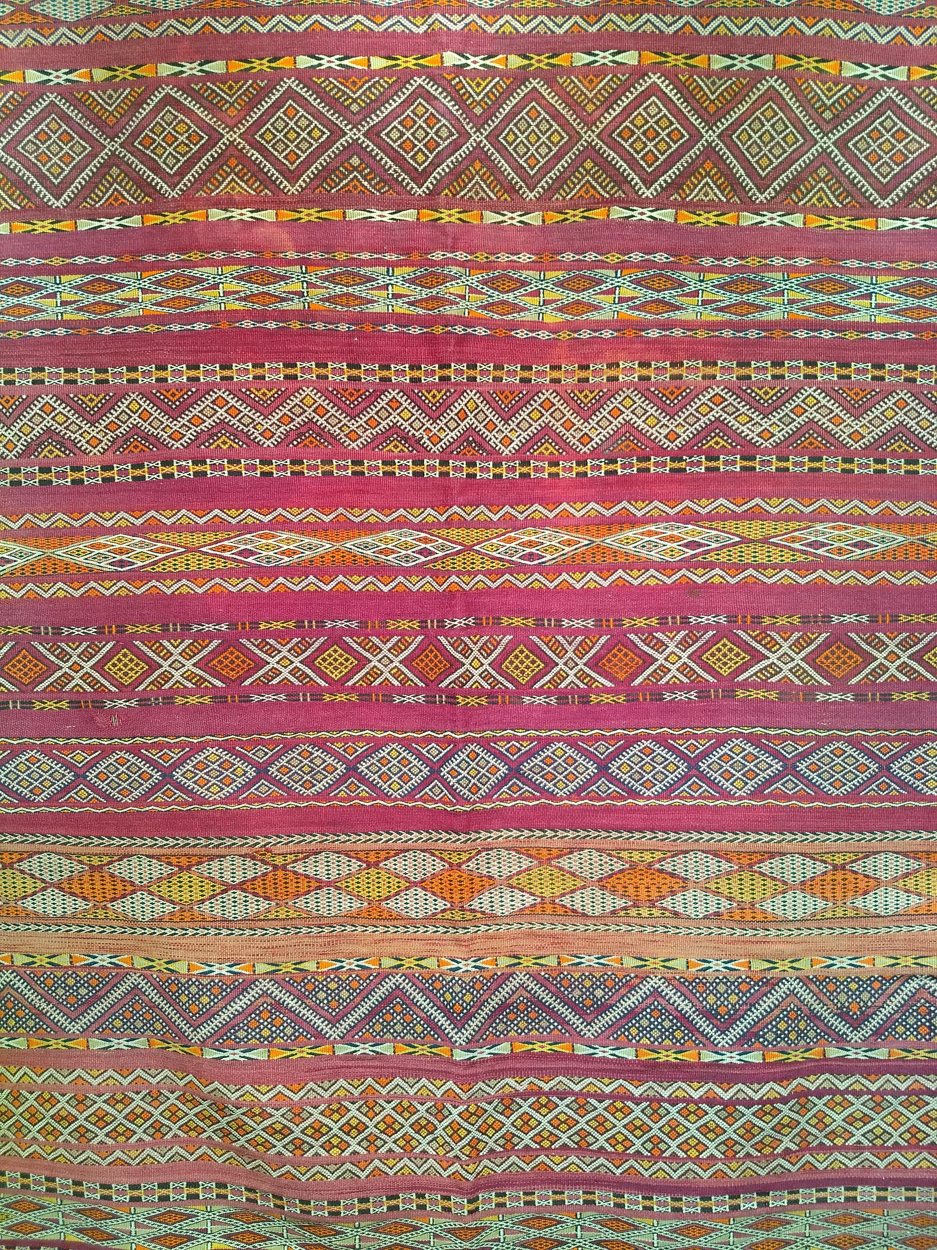 Beautiful and colorful vintage Moroccan kilim with multiple stripes with various detailed geometric designs in each band.   The range of colors in the Moroccan kilim includes purple, red, yellow, and ivory.   The size of the rug makes it ideal