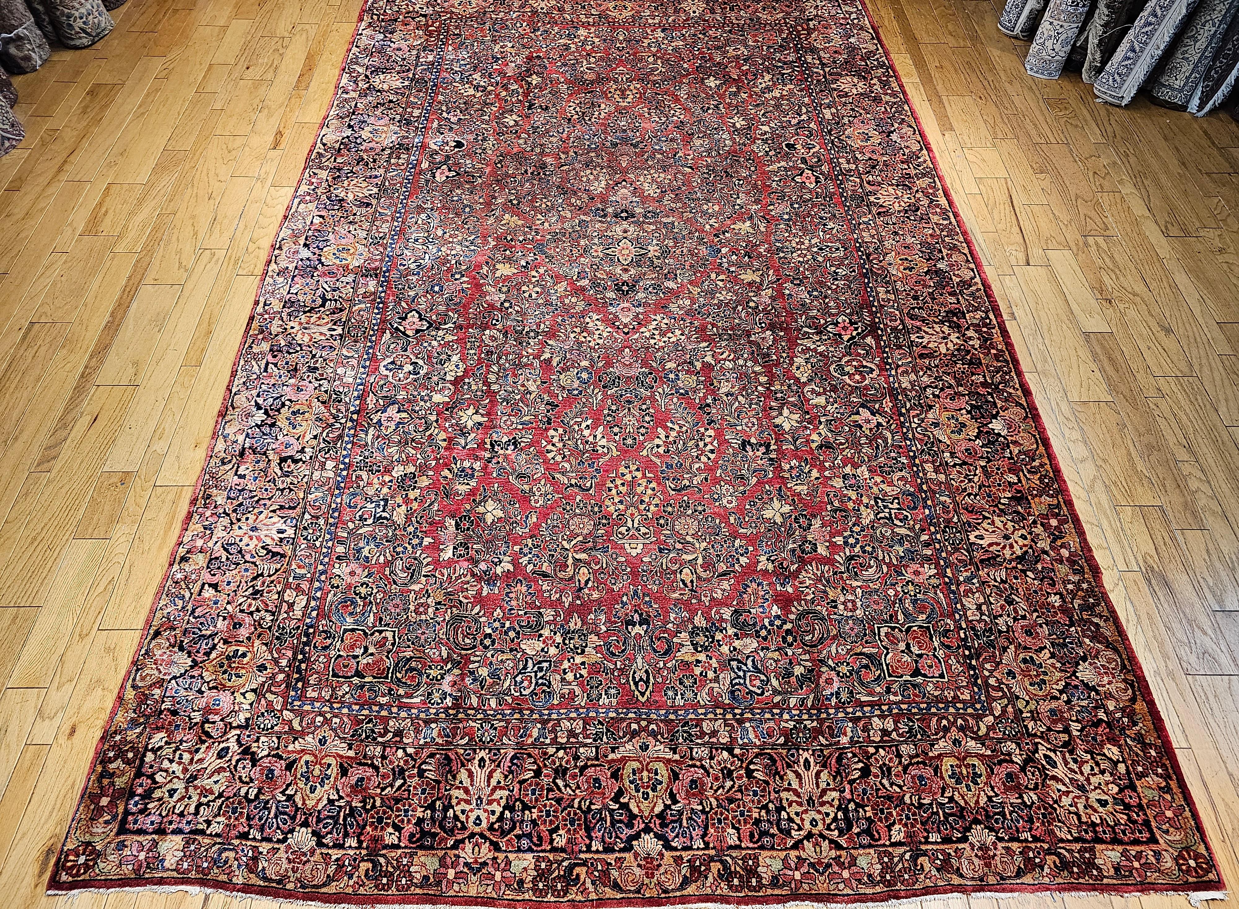 Vintage oversized Persian Sarouk  has an all-over pattern consisting of large flower bouquets in red with a dark blue border also filled with flower bouquets.  The Sarouk rugs have the flower bouquet and vase design mostly in a dark red background