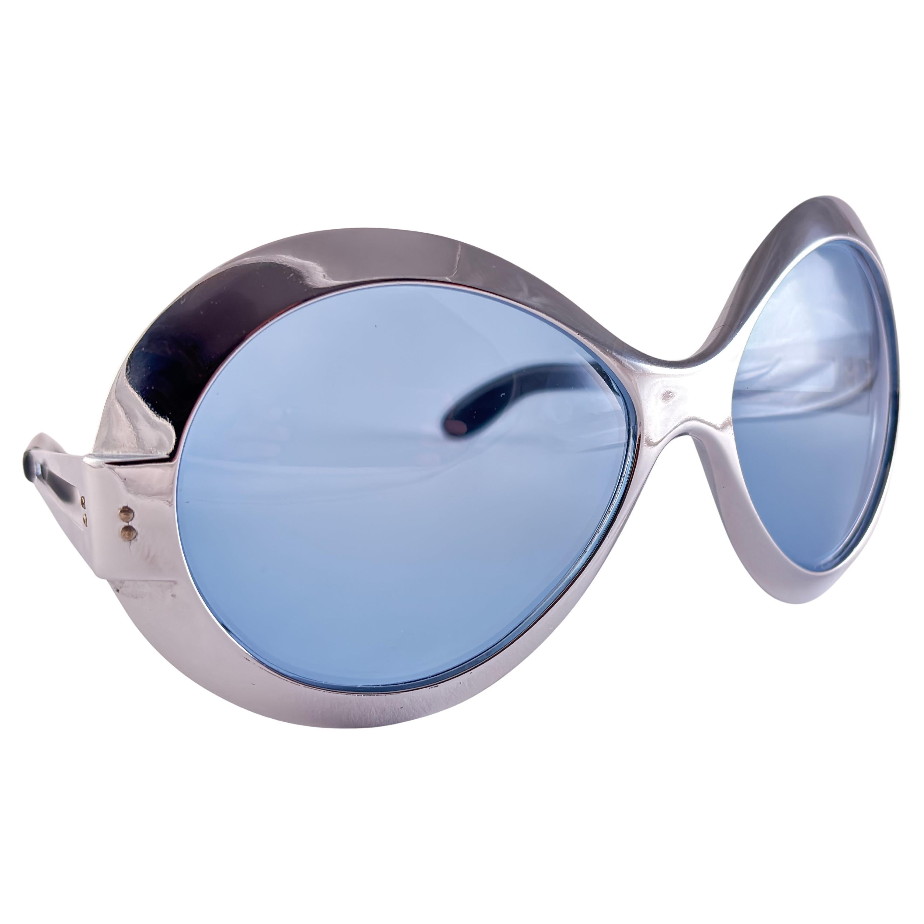 Gafas de sol plateadas metalizadas de gran tamaño Uber. Lentes azul bebé.

Este artículo tiene pequeños signos de desgaste en el marco debido al almacenamiento.

Medidas 

Frente : 18,5 cm 
Altura de la lente : 6 Cms
Anchura de la lente : 7