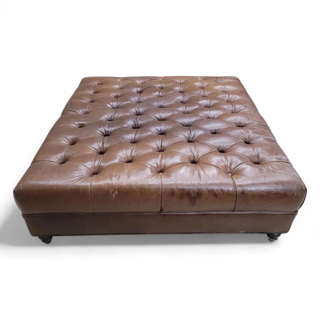 Ottoman/table basse en cuir vieilli surdimensionné et touffeté vintage sur pieds tournés

Cet ottoman vintage surdimensionné en cuir vieilli et touffeté peut servir de table basse ou d'ottoman. Soutenu par de robustes pieds tournés, ce meuble ne se