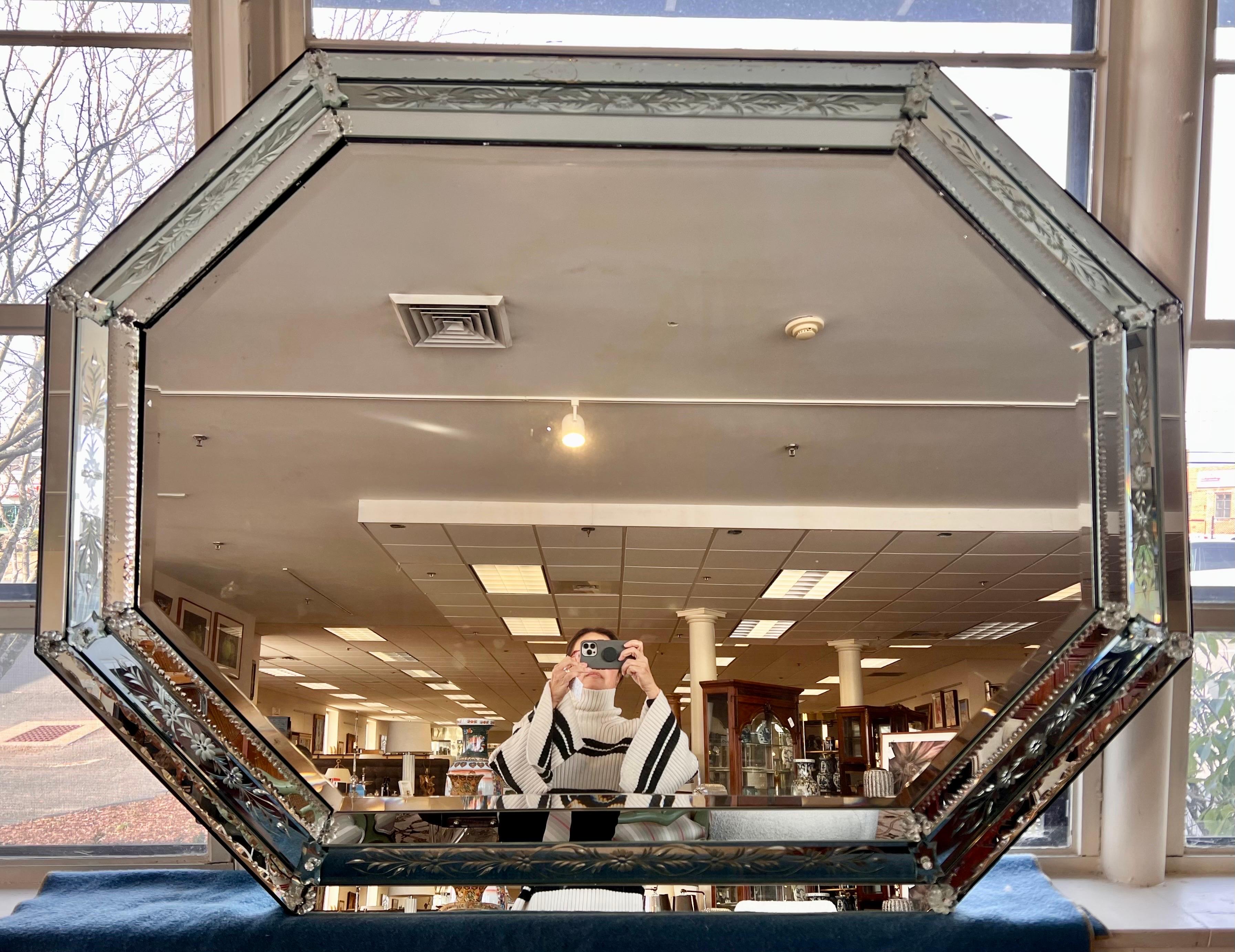 Spectacular midcentury oversized Venetian mirror has a delicately paned triple glass frame surrounding a central beveled mirror. Features an engraved floral motif and is trimmed with rosettes. Beautiful detail all around.