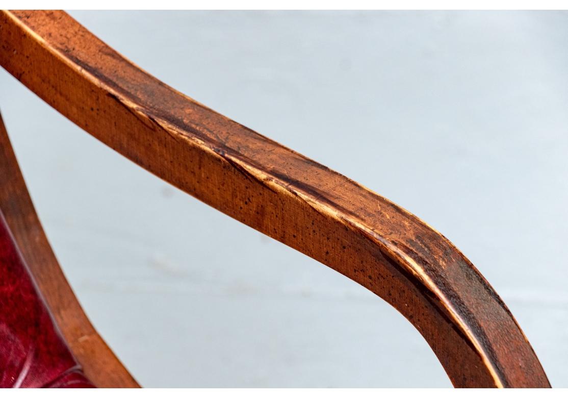 Chaise longue ou traîneau Chesterfield d'époque caractérisée par une profonde tapisserie en cuir boutonné, une assise basse, des décorations en laiton, des accoudoirs à volutes profondes et reposant sur des brancards tournés avec un pied en