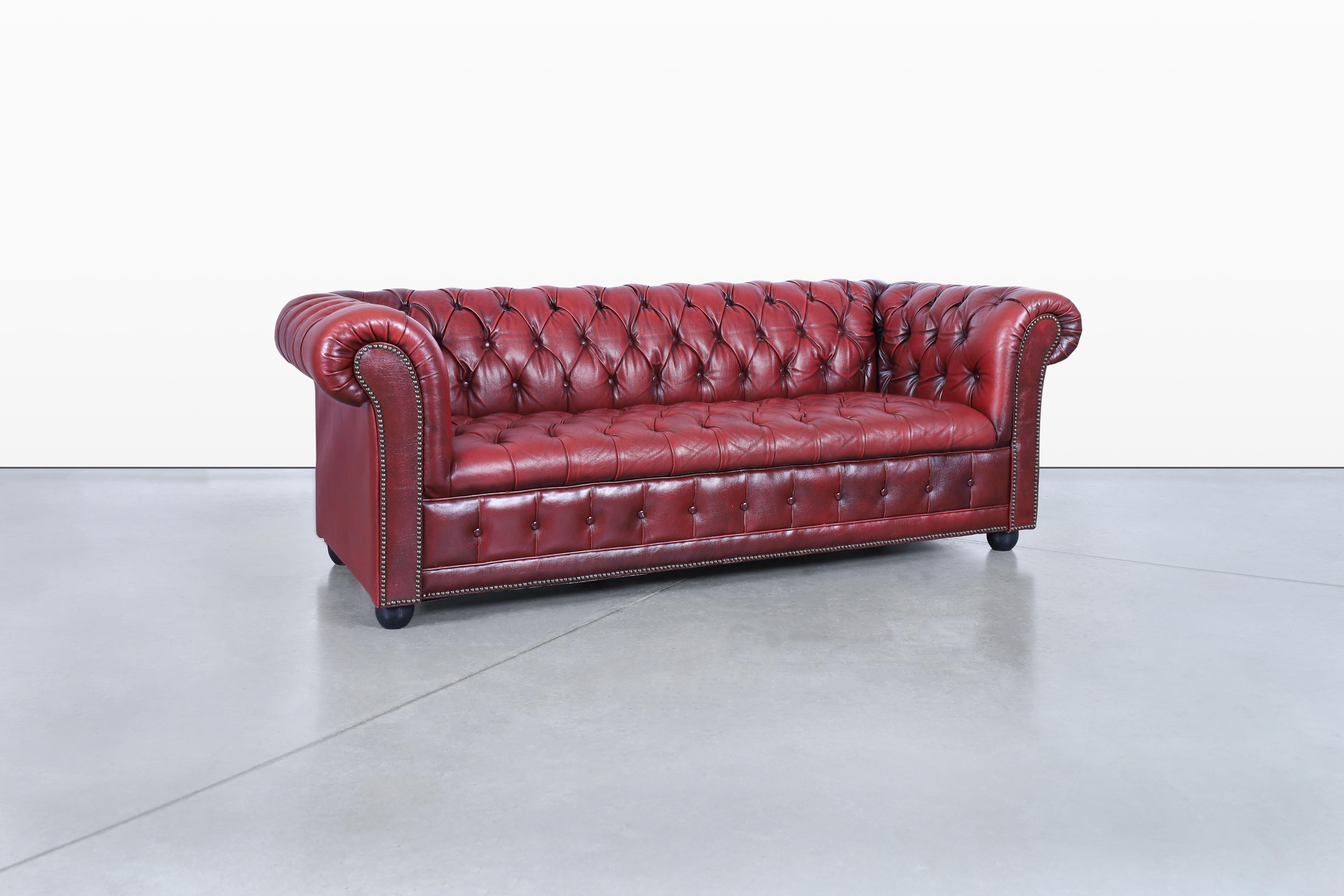 Discover the timeless charm of this elegant vintage leather Chesterfield sofa, expertly crafted in the United States during the 1960s. Its striking design features a captivating arrangement of deep tufted diamond upholstery that enhances its