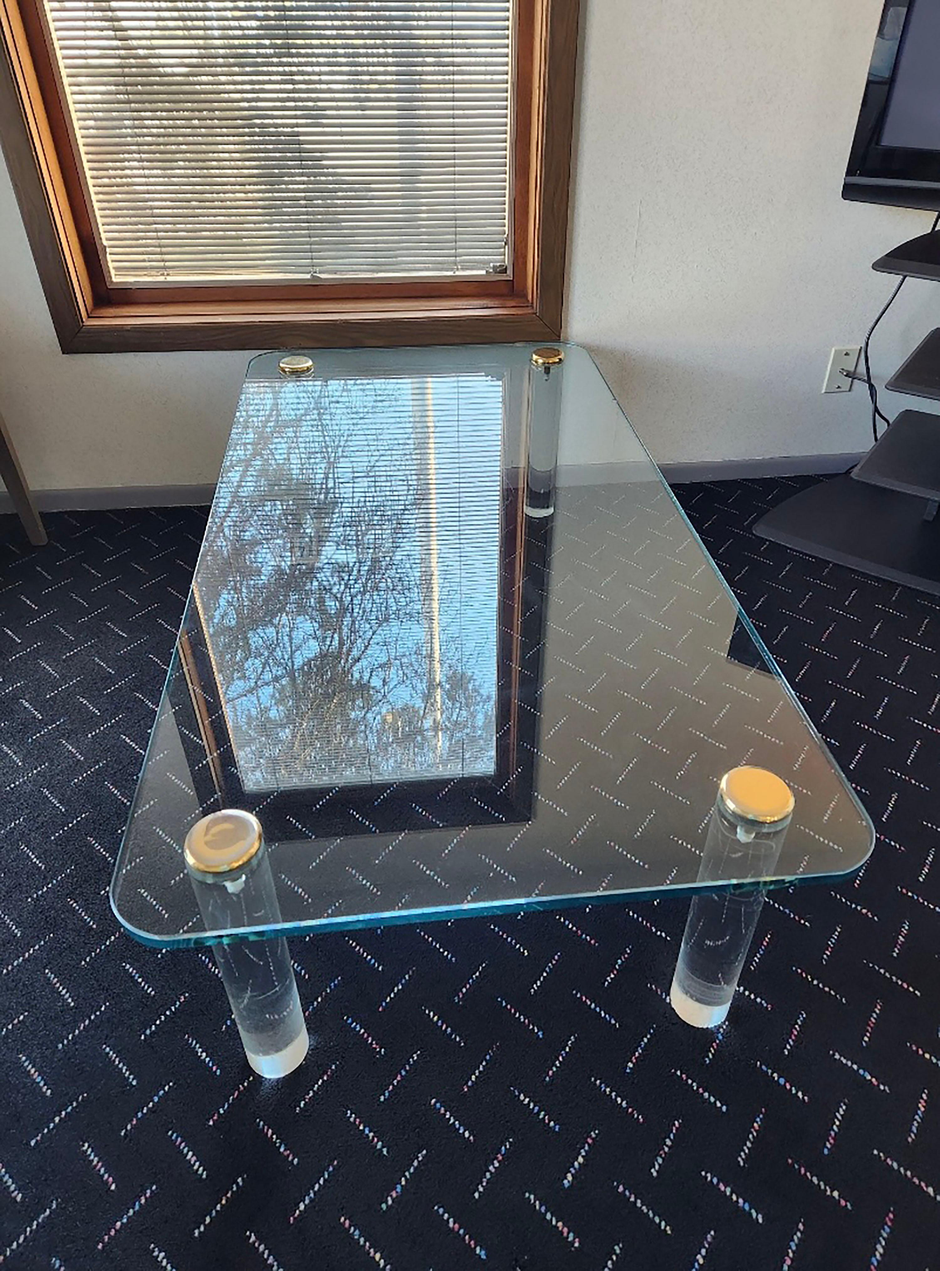 Vintage glass coffee table by Leon Rosen for Pace. Lucite Legs with Brass caps. All very high quality.

Glass has a notable shallow chip on underside of one edge. Shown circled in red. Could possibly be buffed out by a glass house. A new piece of