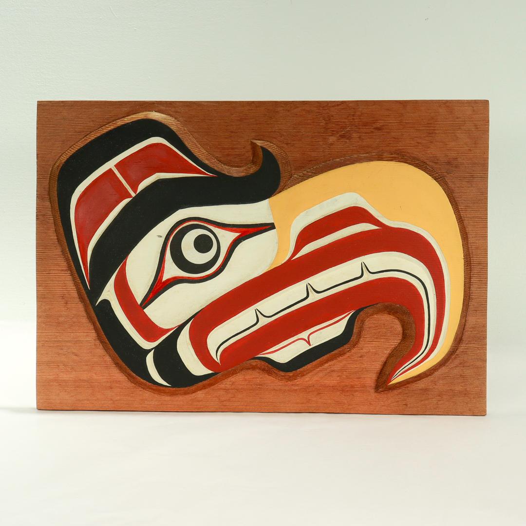 A fine vintage Pacific Northwest Native wooden carving.

The carving in the form of an hawk with red, black, white, and yellow tones set on a brown wooden board.

By William Wasden Jr. 

Wasden was trained from a very young age in numerous artistic