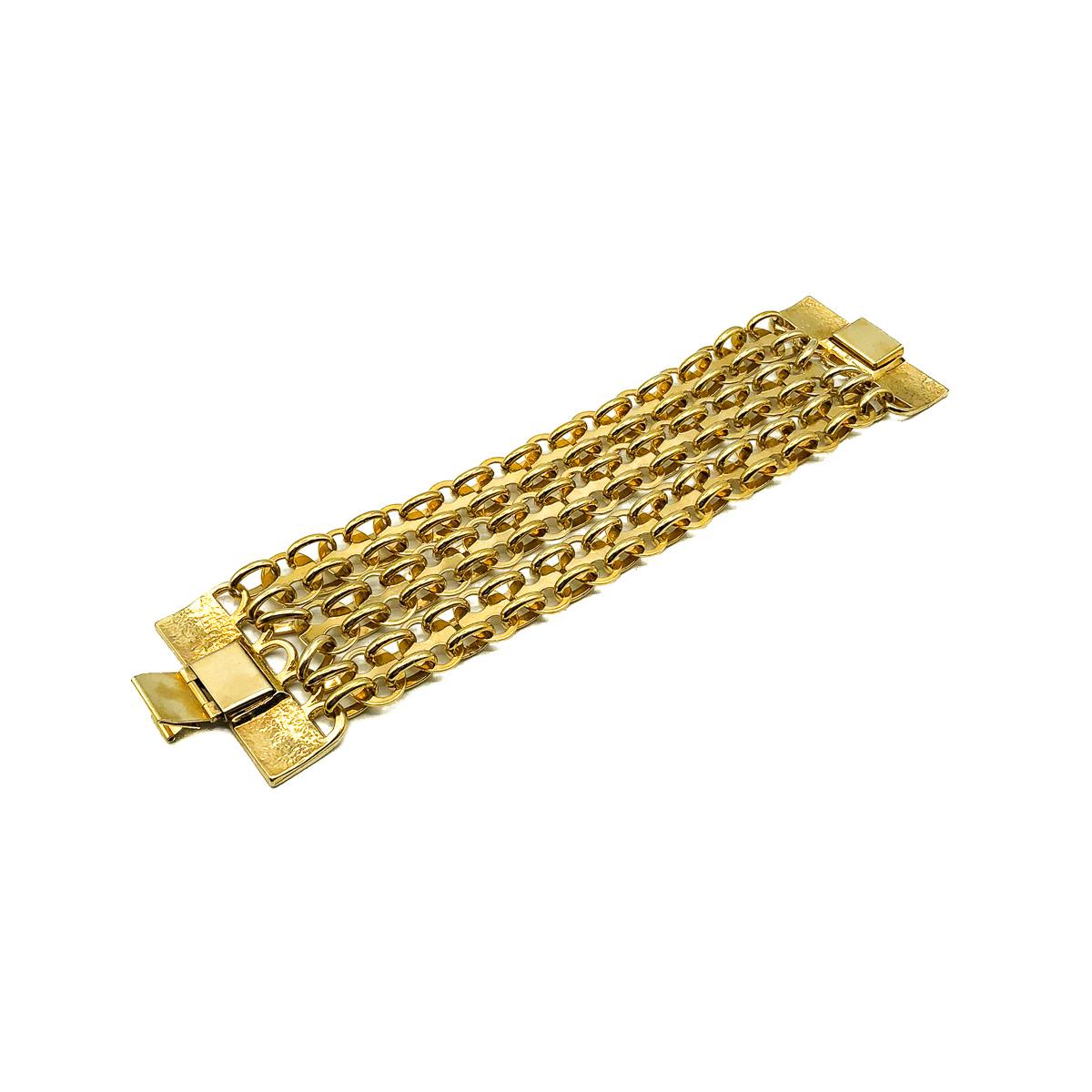 A Vintage Paco Rabanne Bracelet oozing the bold metallic sculptural style now so iconic of this cutting edge Parisian Fashin House. Featuring triple ornate chains in a chain mail formation suspended from statement logo clasps. Crafted in gold plated