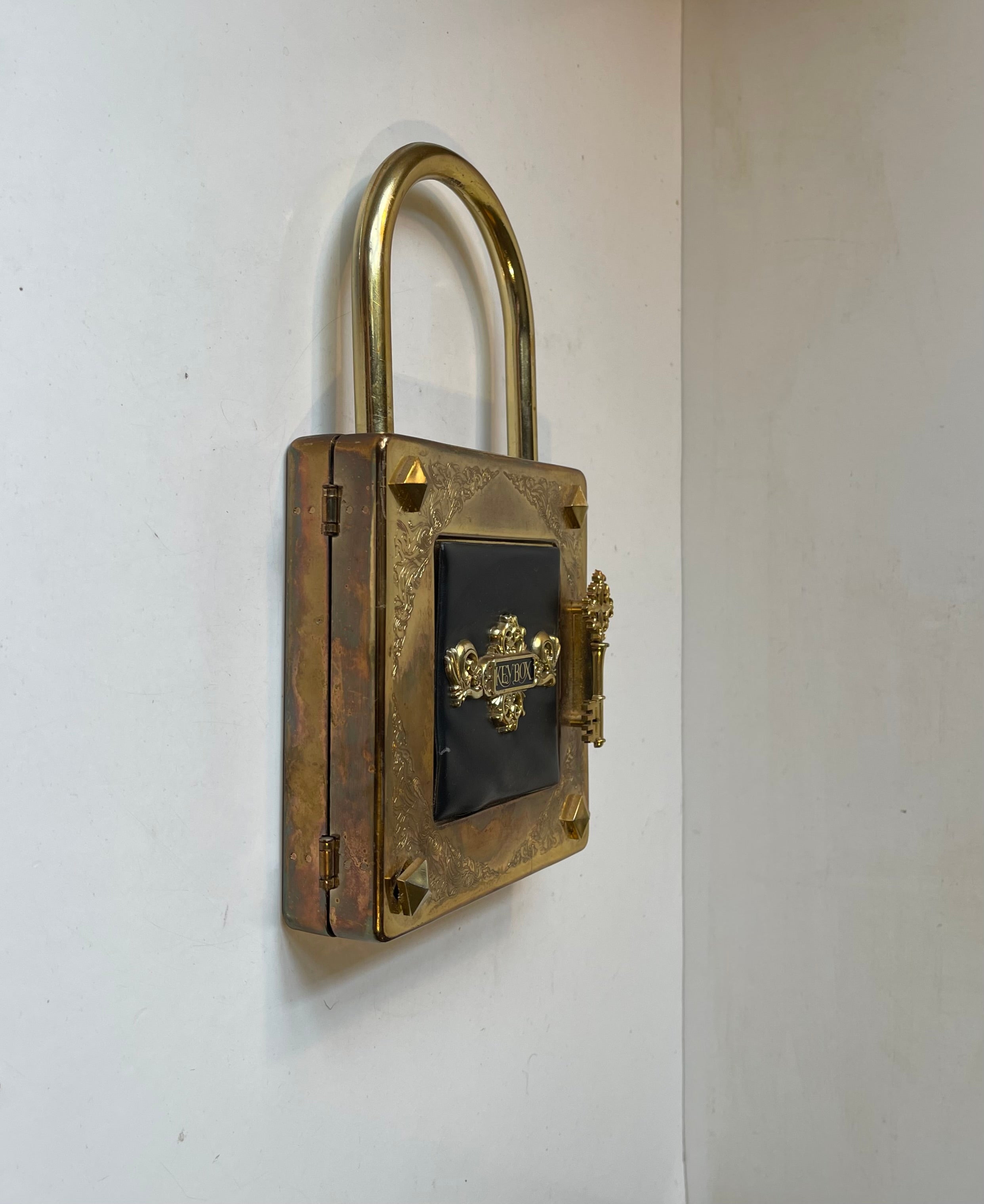 Japanese novelty wall mounted key hanger in the shape of this jumbo padlock in patinated brass. Curious details with xl revits and key.shaped handle. Intact black acrylic-lined interior with note-blok and 7 key-hooks. Made in a midcentury style in