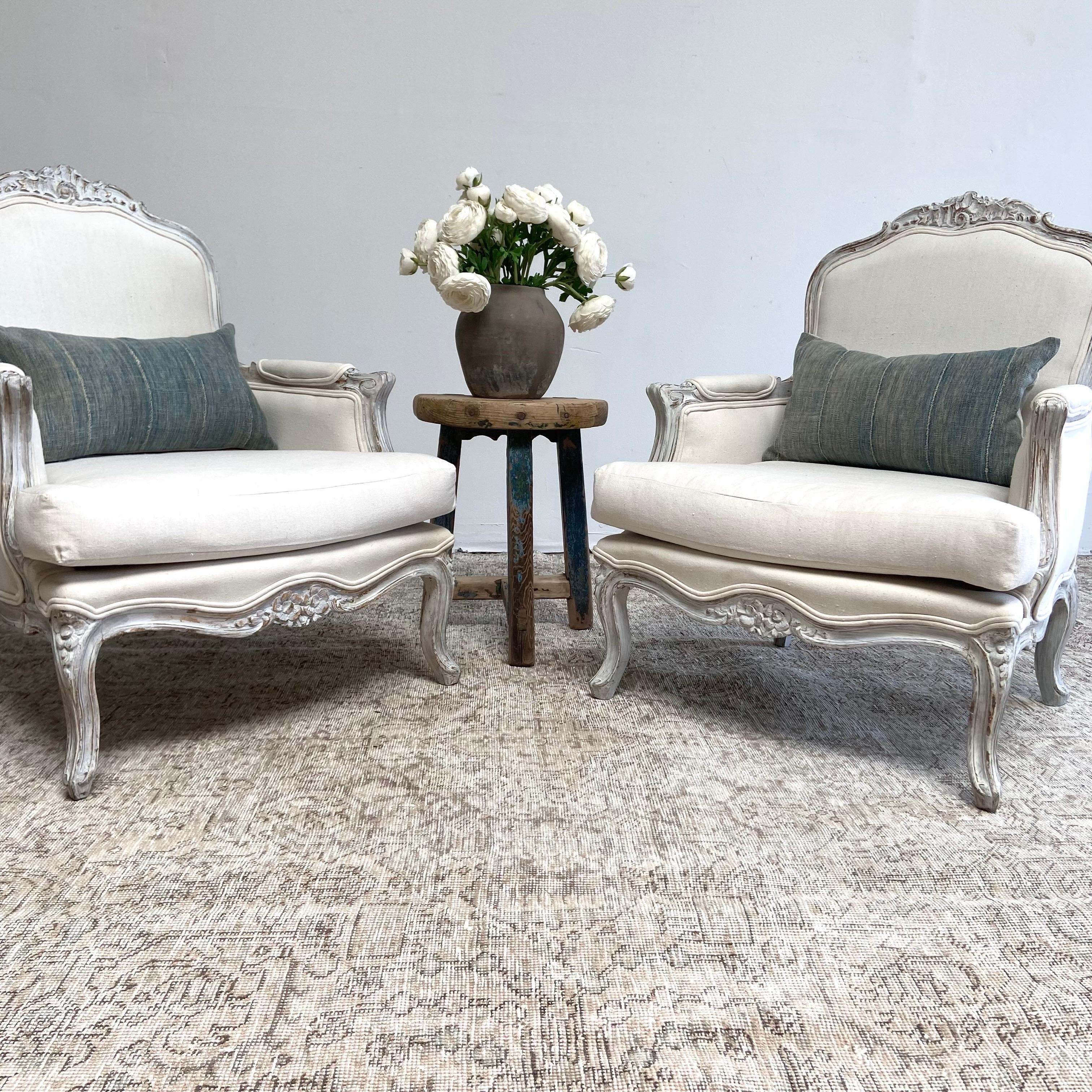Pair open french style bergere chairs. Louis XV Style with painted gray finish with subtle distressed edges, and cotton upholstery. Legs are solid and sturdy ready for everyday use. These can be reupholstered in any of our linens, velvets, or