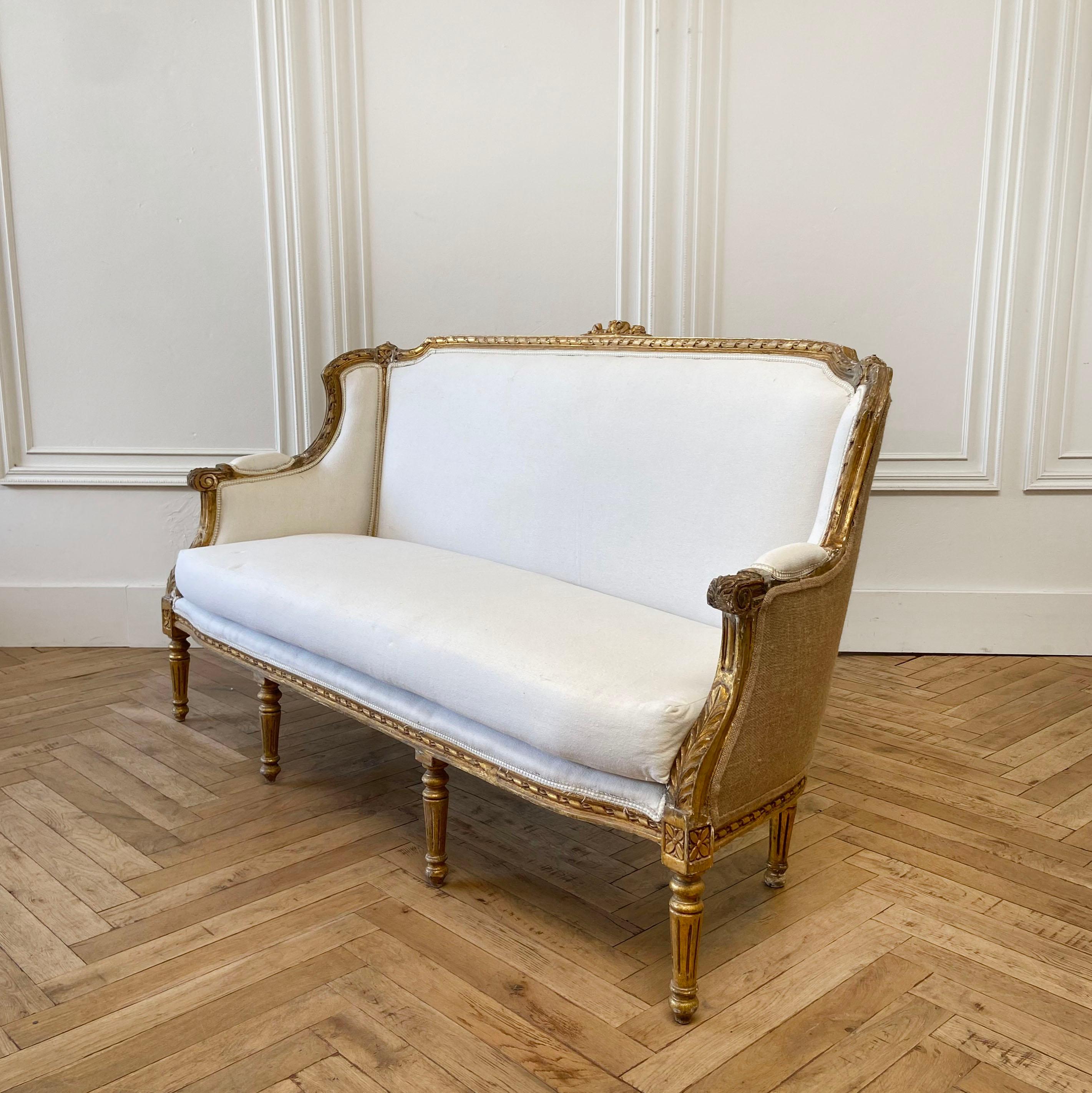 Vintage painted and upholstered Louis XVI style sofa settee.
Original gilt wood finish with subtle distressed edges. Classic fluted legs, with rose carvings. Upholstered in a natural muslin fabric.
Measures: 67” W x 30” D x 38” H
Seat height: