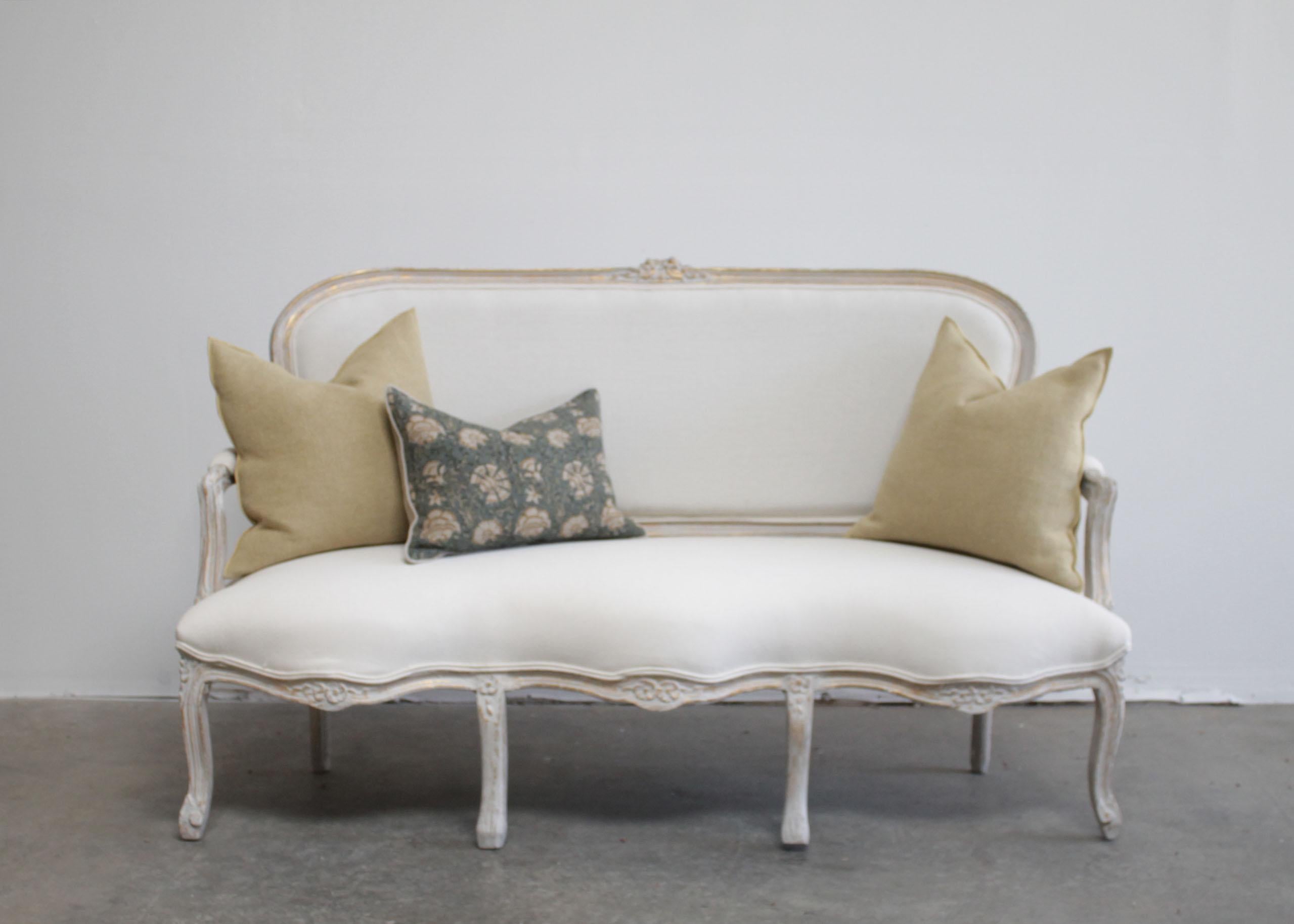 Vintage painted and upholstered Louis XV style open arm sofa settee.
Painted in a French gray with subtle distressed edges, where gilt and wood show through.
Classic cabriole carved legs, with a floral carvings, and large double flower carving at