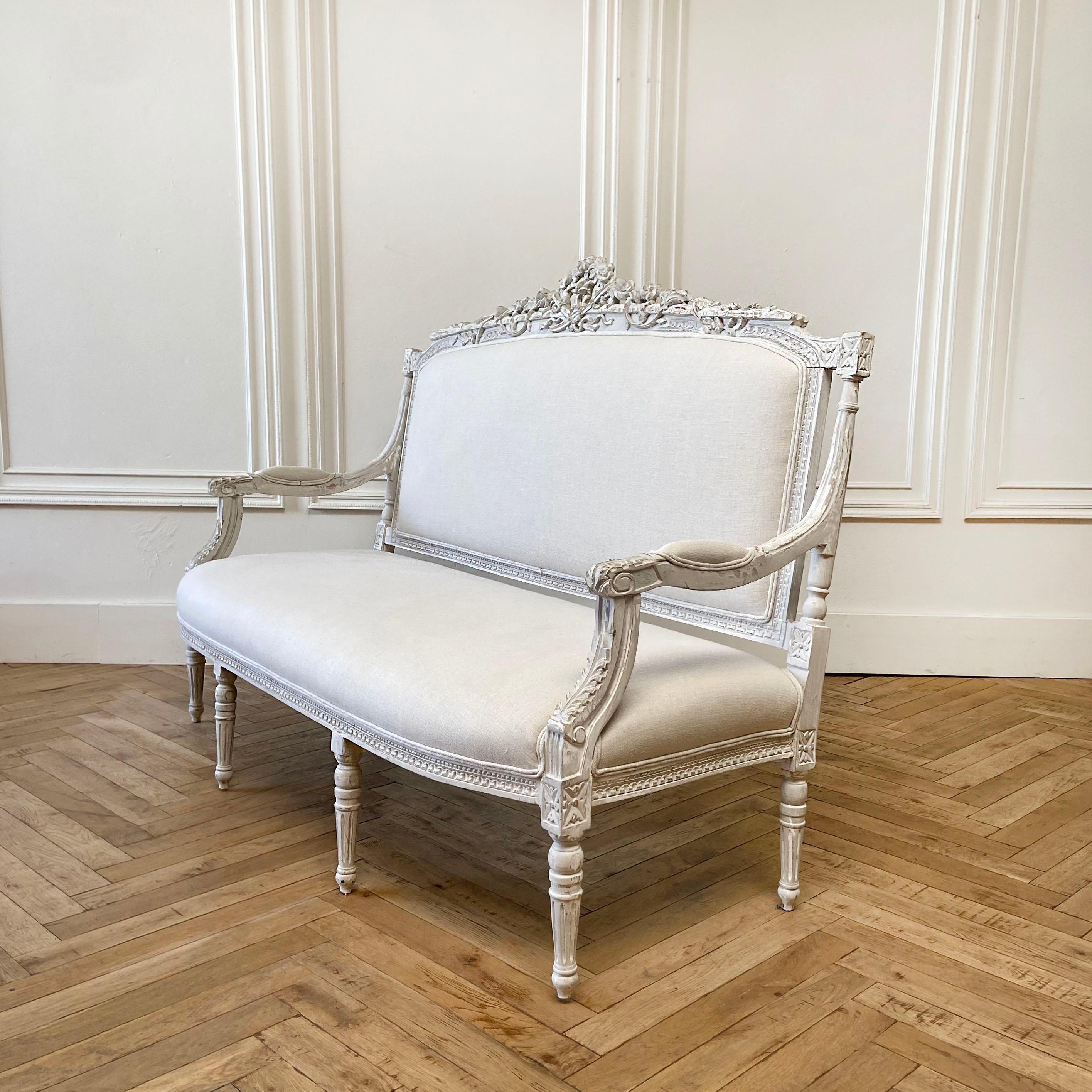 Vintage painted and upholstered Louis XV style open arm sofa settee Painted in a French gray with subtle distressed edges, where gilt and wood show through. Classic Louis XV legs, with a medallion carving, and large rose and flower garland trailing