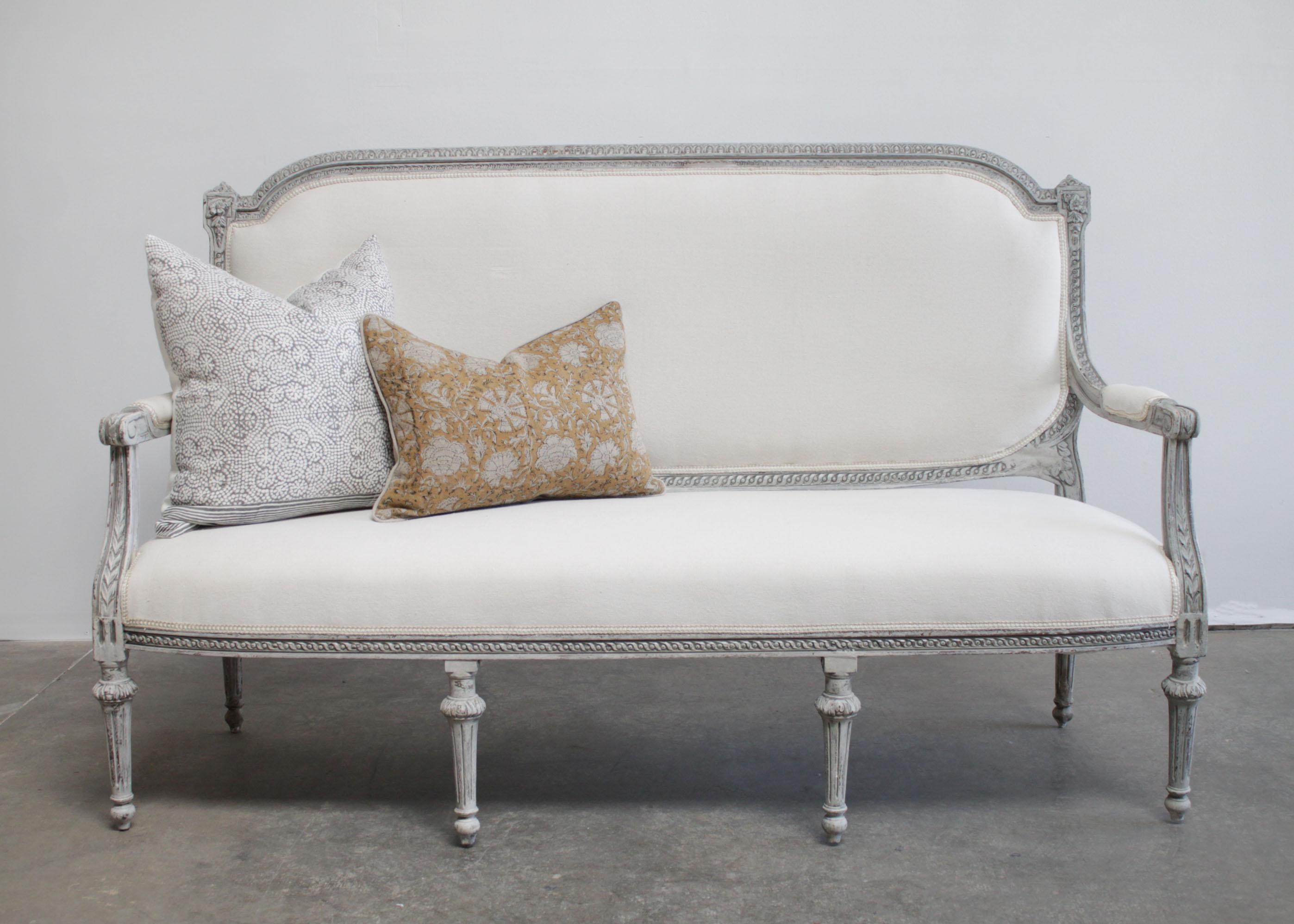 Vintage painted and upholstered Louis XVI style open arm sofa settee
Painted in a Gustavian gray with subtle distressed edges.
Classic fluted legs, with a medallion carving. A detailed carved frame with egg and dart carvings, and floral carved