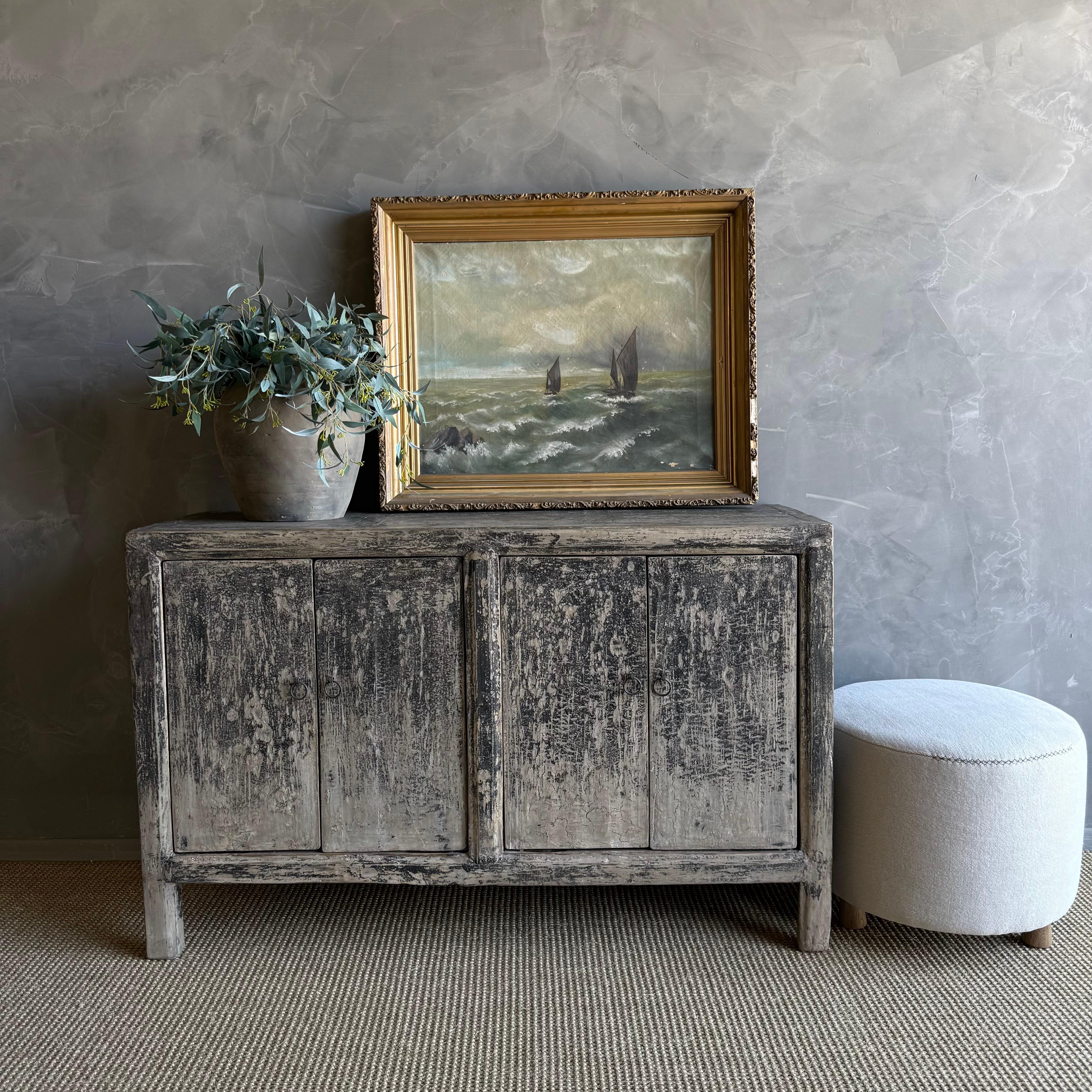 This charming vintage elm wood cabinet is a one-of-a-kind piece with beautiful age and patina that adds character to any space. Its patina painted elm wood finish showcases the natural beauty of the wood, while the solid elm wood original hardware