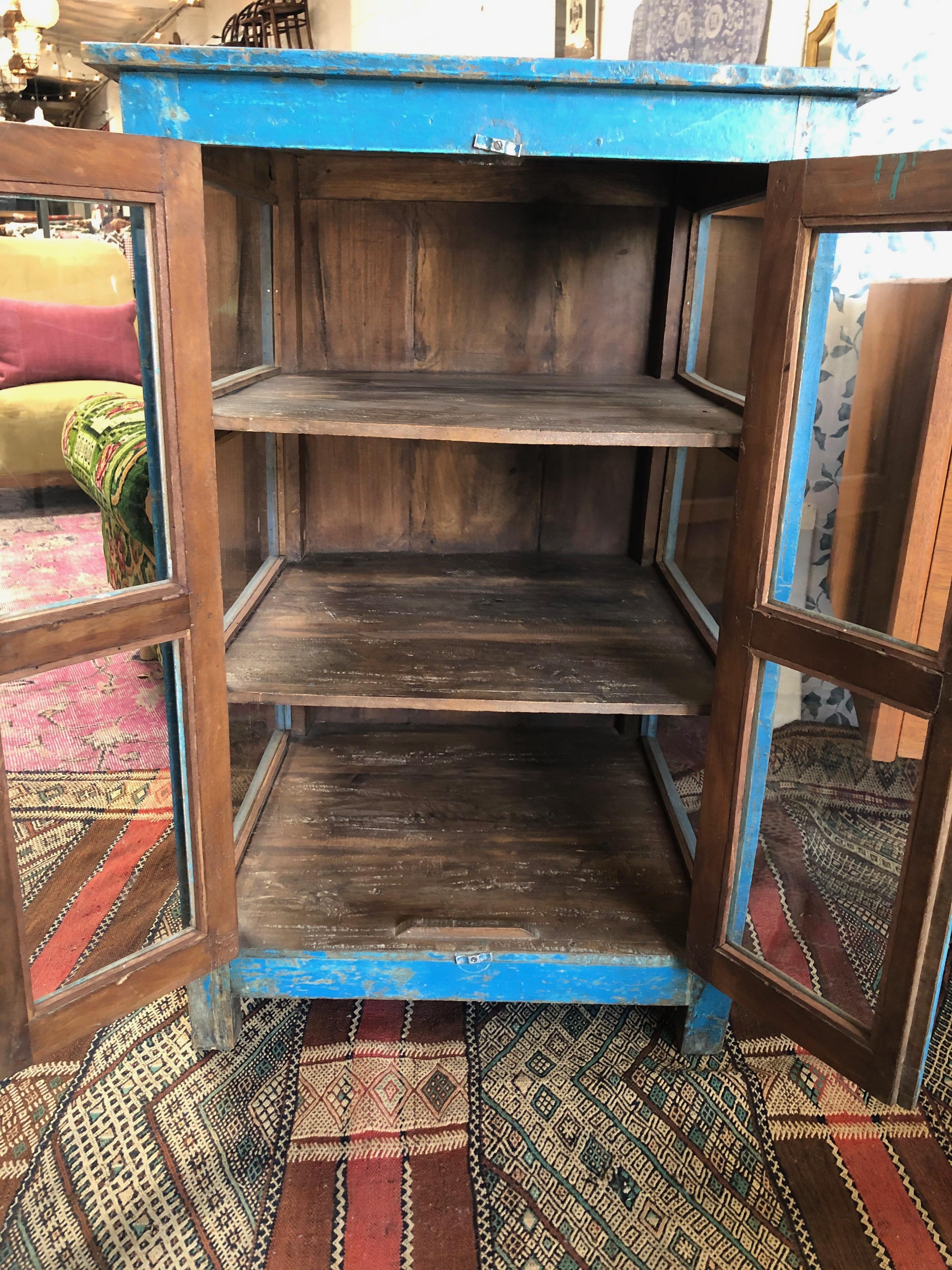 This vintage wooden hand painted blue cabinet features three shelving units and pull-open doors. Perfectly aged and a great addition to any rustic or farmhouse styled space.