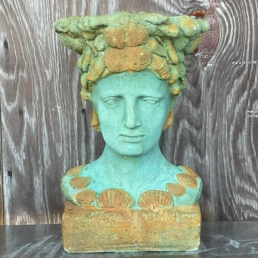 Diese bemalte Büste aus Beton im Vintage-Stil ist eine beeindruckende Mischung aus Kunst und Funktion. Die sorgfältig gearbeitete Büste mit Muschel- und Korallenmotiven weist eine verwitterte grüne Patina auf, die den Charme der Küstenlandschaft