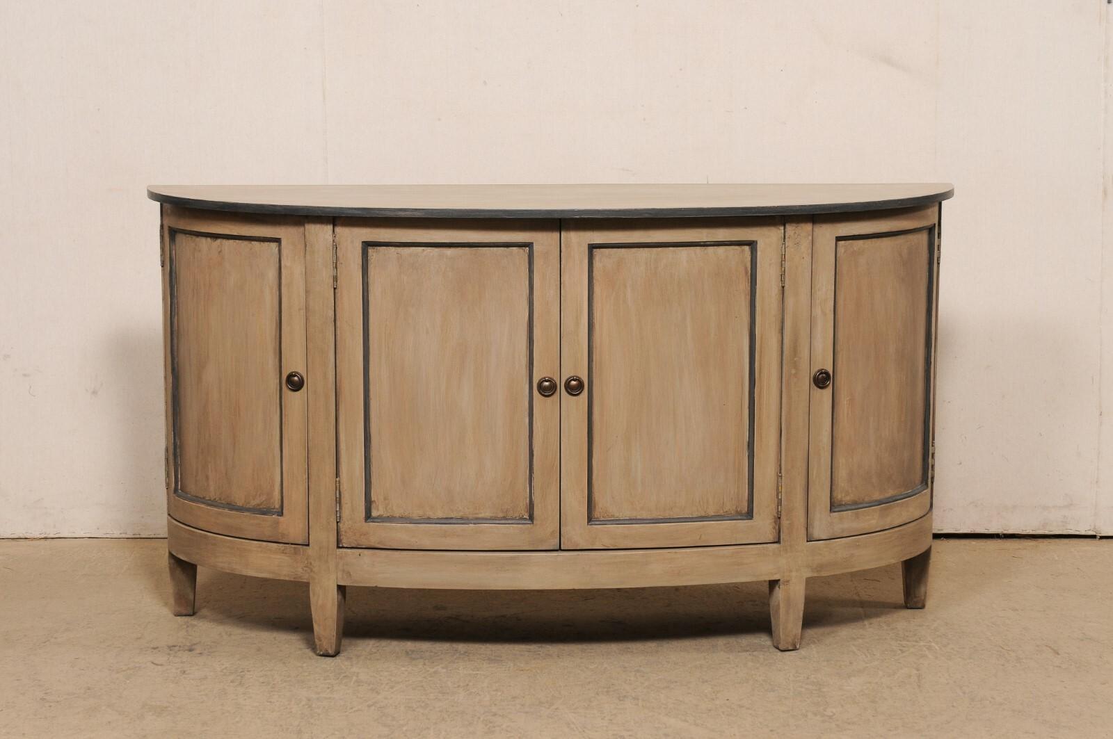 An American painted wood demi-lune console cabinet, minimally adorn in clean lines. This vintage American made cabinet has an oblong demi shape, with flattened backside as to rest snuggly against a wall. The top overhangs the case below which houses