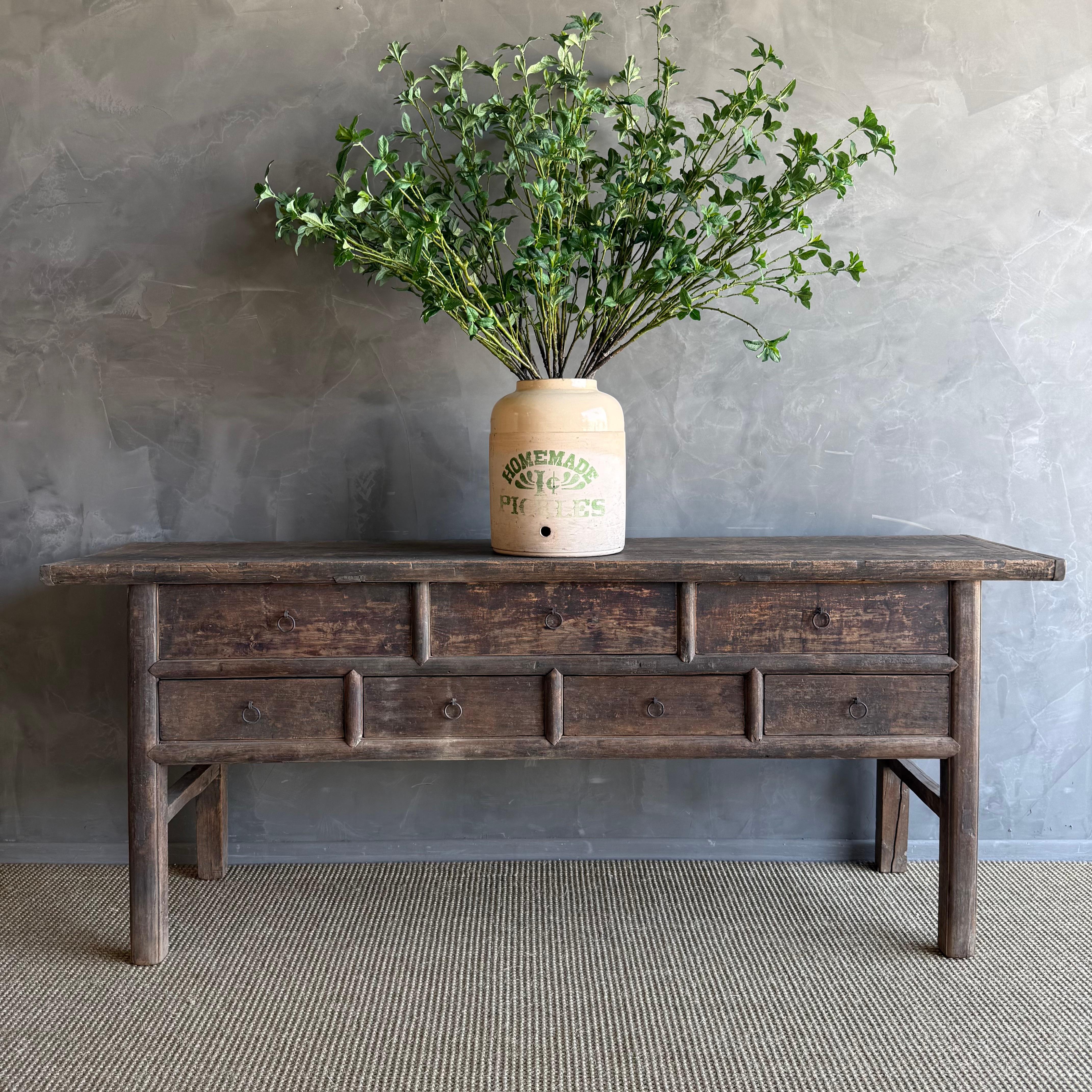 This charming vintage elm wood console is a one-of-a-kind piece with beautiful age and patina that adds character to any space. Its patina painted elm wood finish showcases the natural beauty of the wood, while the solid elm wood original hardware