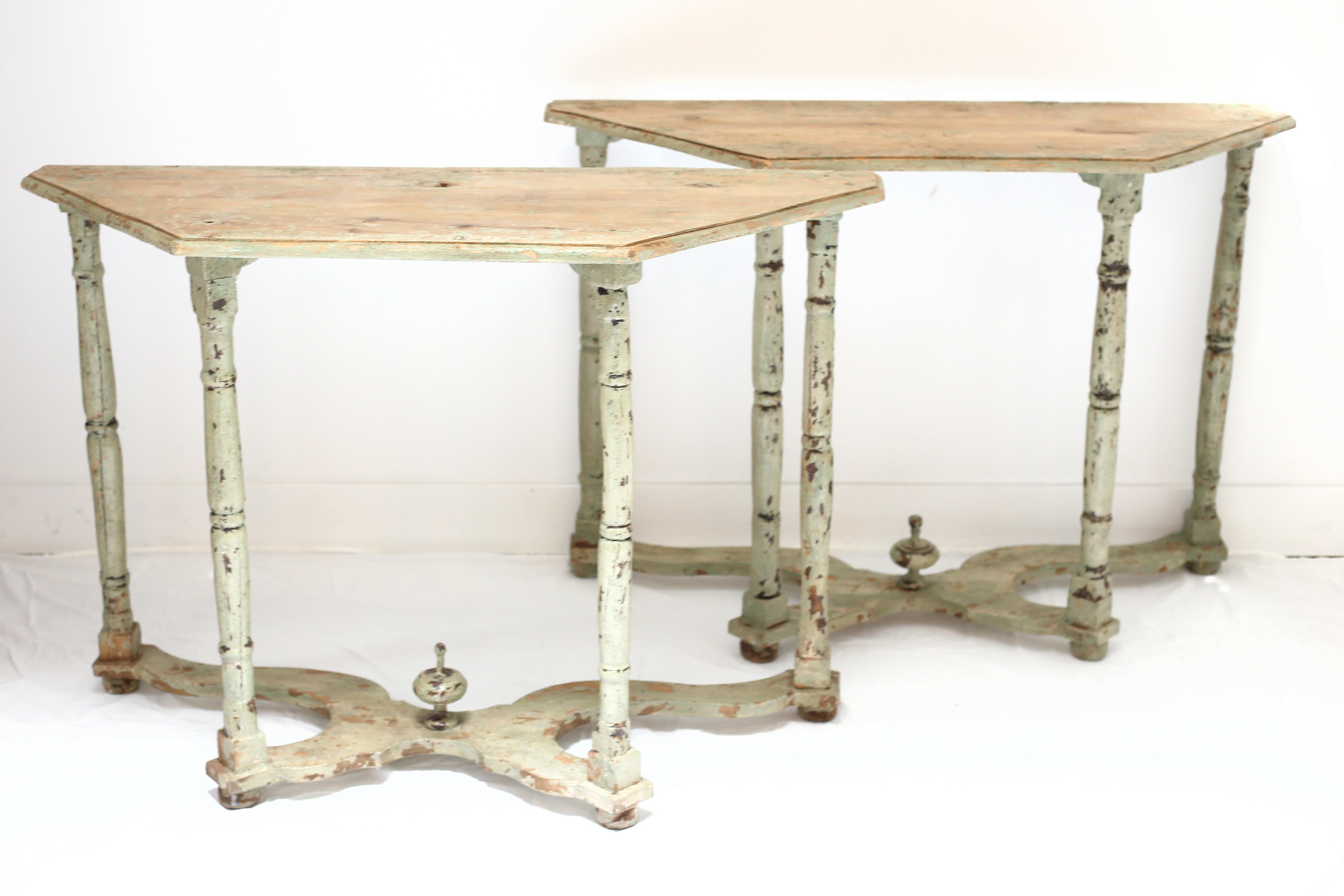 Pair of European vintage console tables with chippy, distressed pale green paint finish. Curved stretcher and finial detail on the base.
