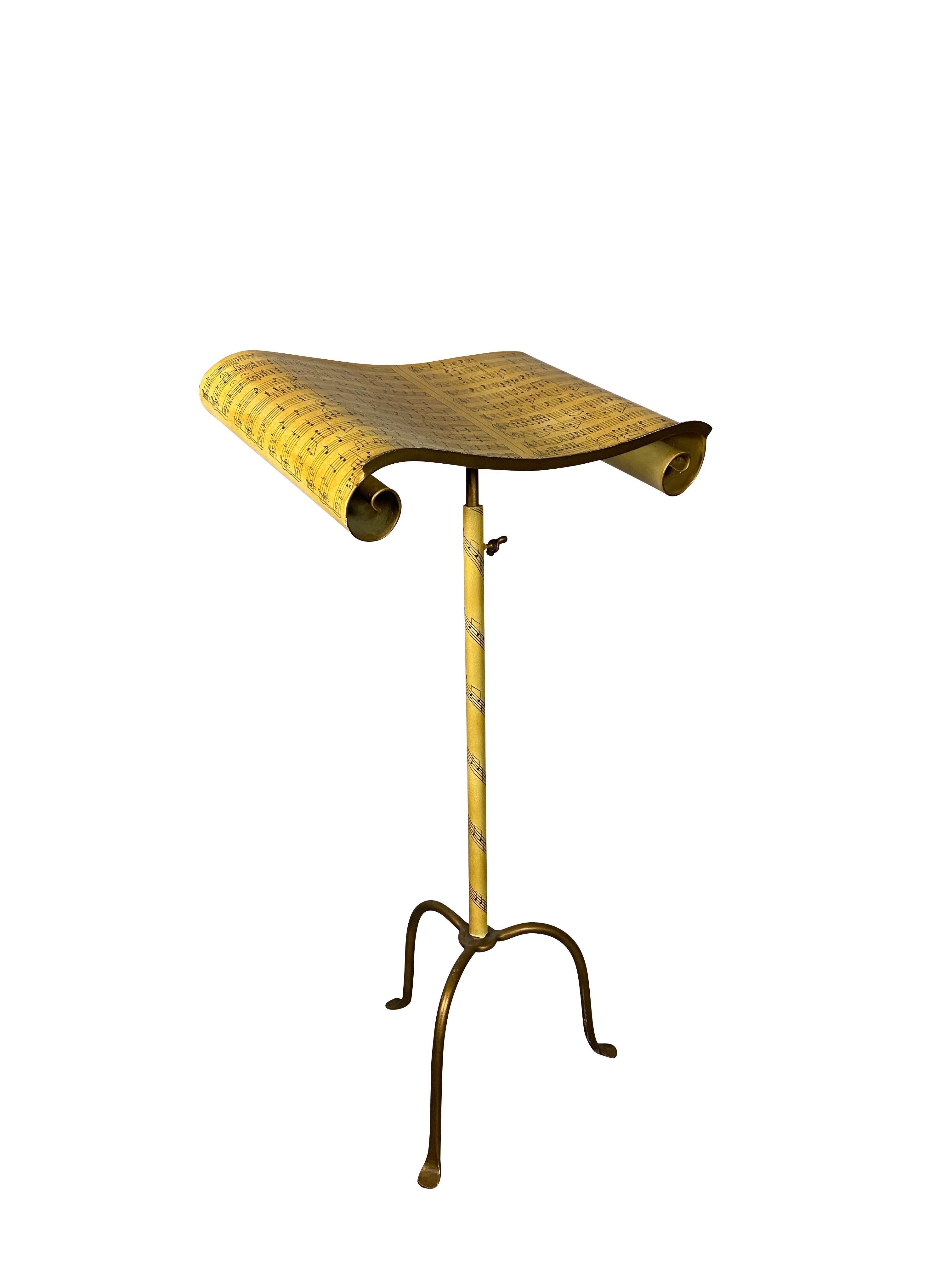 Painted yellow with an adjustable surface decorated and shaped like a piece of sheet music, on a tubular support and tripod support and scroll feet.