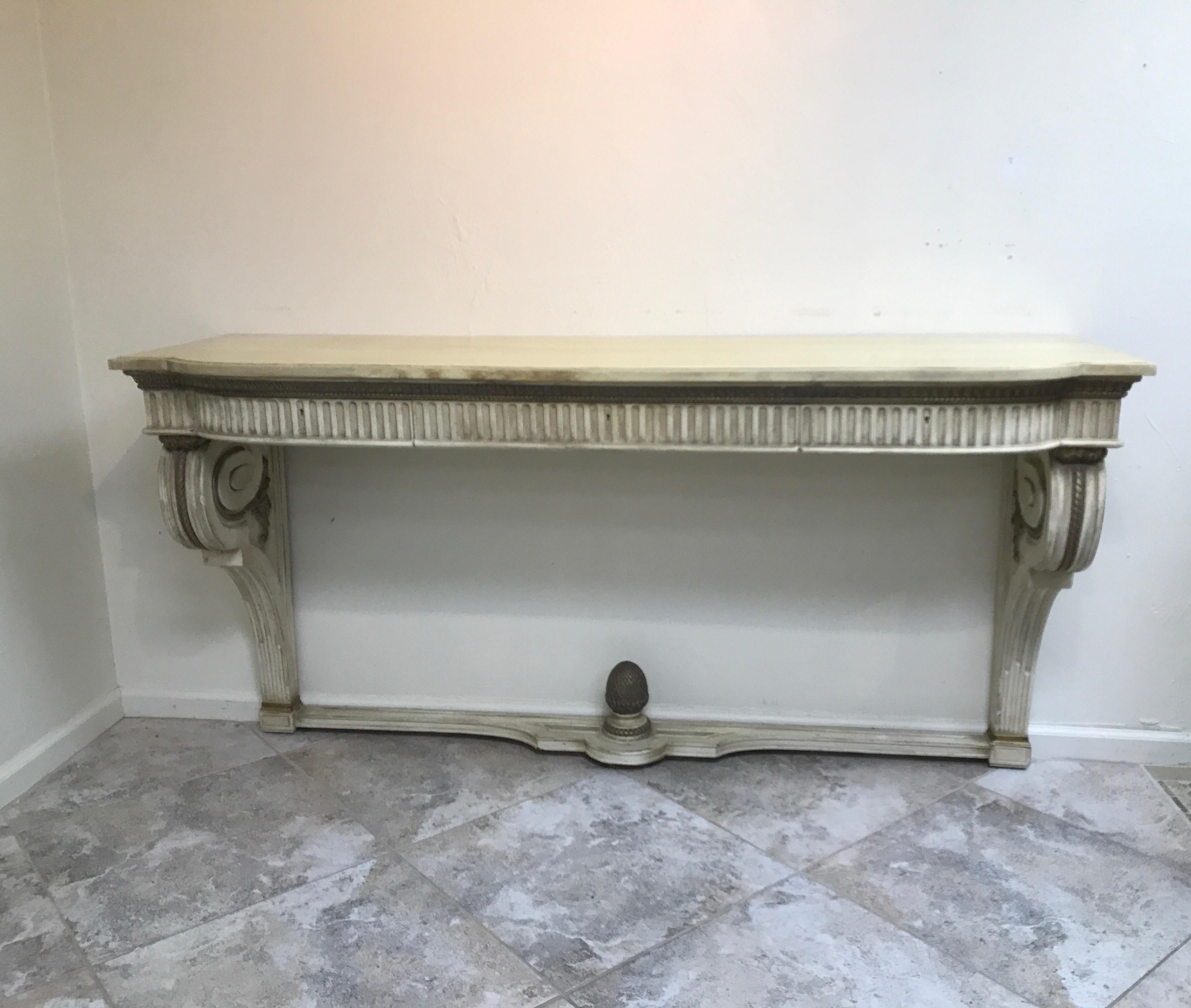 Midcentury painted wood console with faux painted marble top. Console has three ample drawers for storage. It mounts to the wall and features a carved wood gilded pineapple at base.