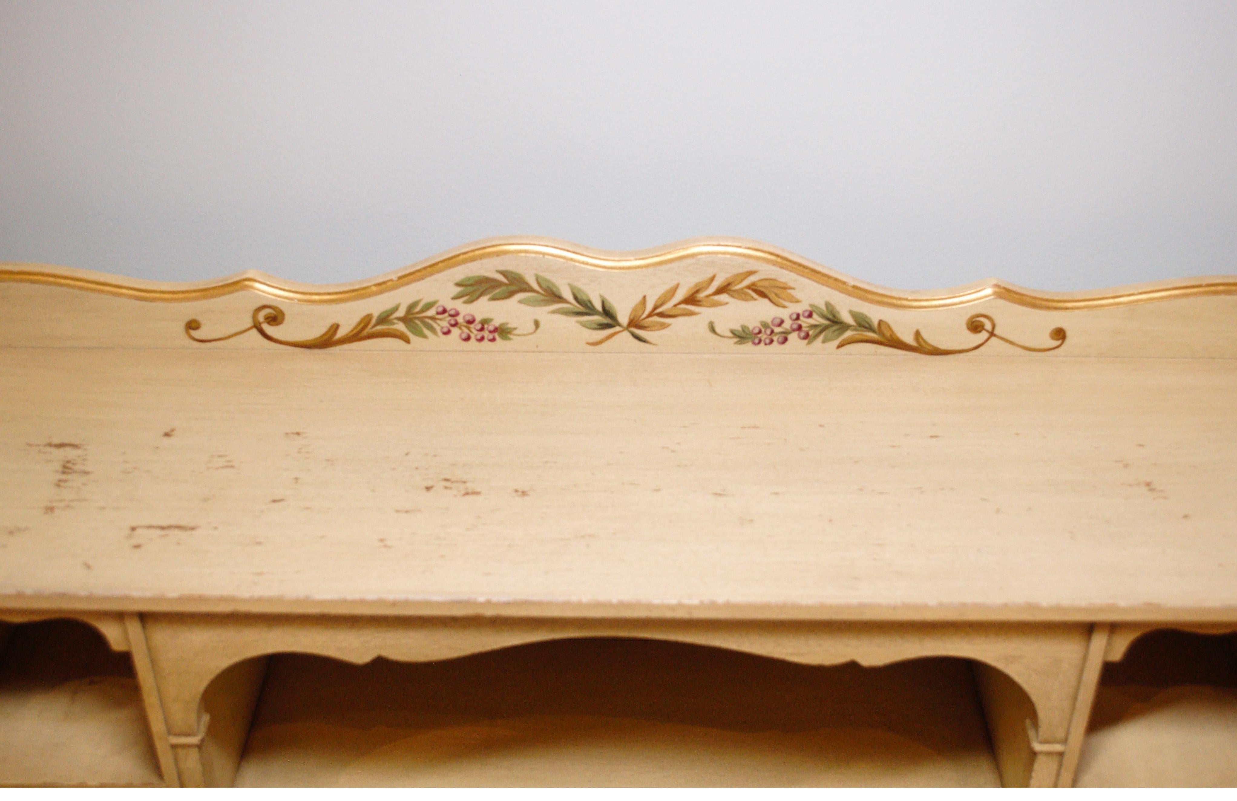 Interesting hand painted writing desk with gallery. The gallery is attached and gives lots of extra storage and display. The solid wood desk has the original hand-painting. The base color is a buttery off-white with natural distressing. The edges