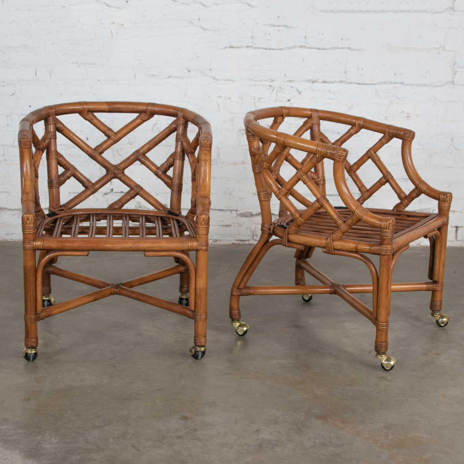 Handsome pair of rattan rolling Chinese Chippendale accent chairs from Wicker by Henry Link. They are in fabulous vintage condition. They wear a pastel floral fabric on their removable seat cushions (which we believe to be a new seat covering and