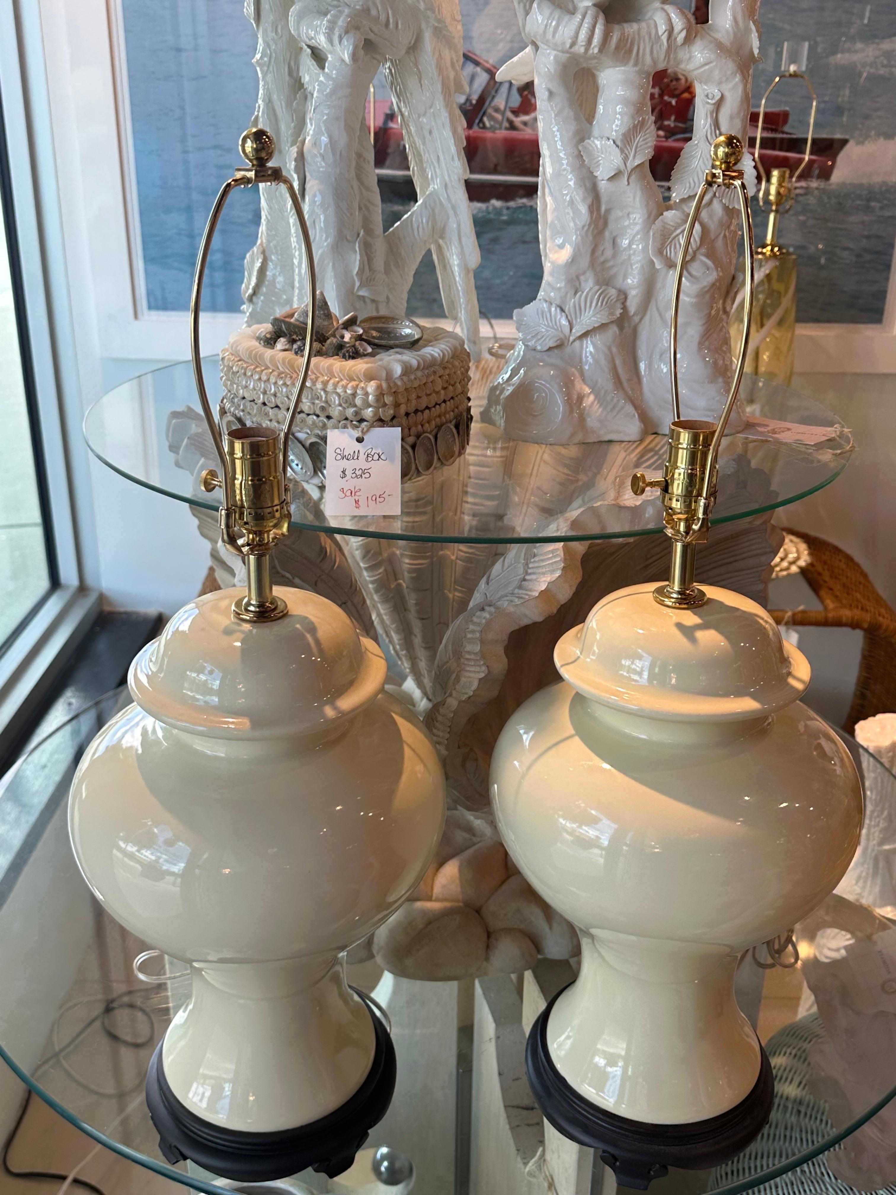 Vintage pair of ivory cream of white ceramic 1970s ginger jar table lamps, wood base. New wired, 3 way sockets, clear cord, all new brass hardware. Small crazing line on back of lamp base, see photo. Dimensions: 27 H (to top of finial) x 20 H (to