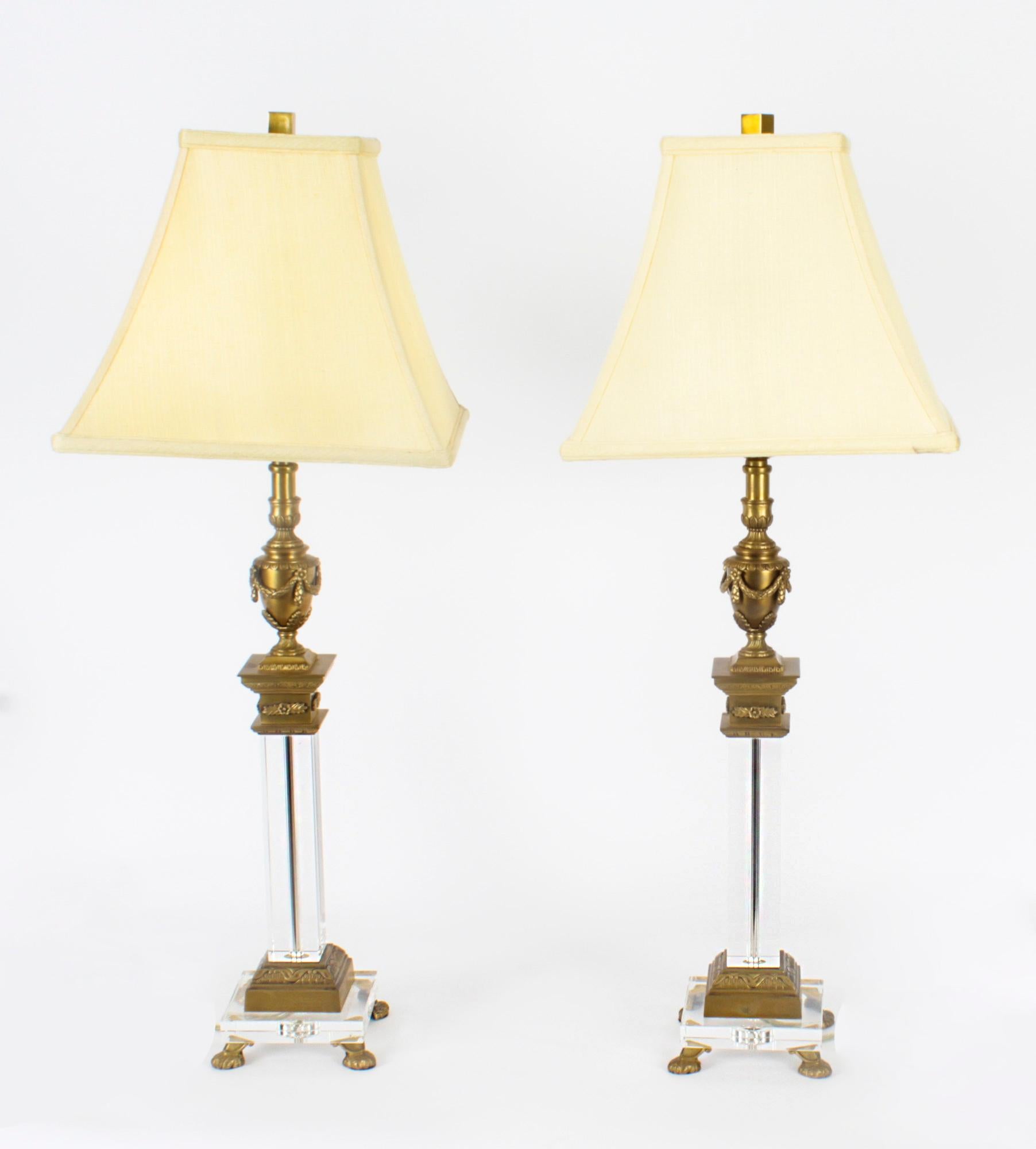 This is an impressive vintage pair of ormolu and glass classical corinthian column & urn table lamp, circa Mid 20th Century in date.

Each lamp features a classical urn capital with swags, above a square shaped Corinthian column decorated with