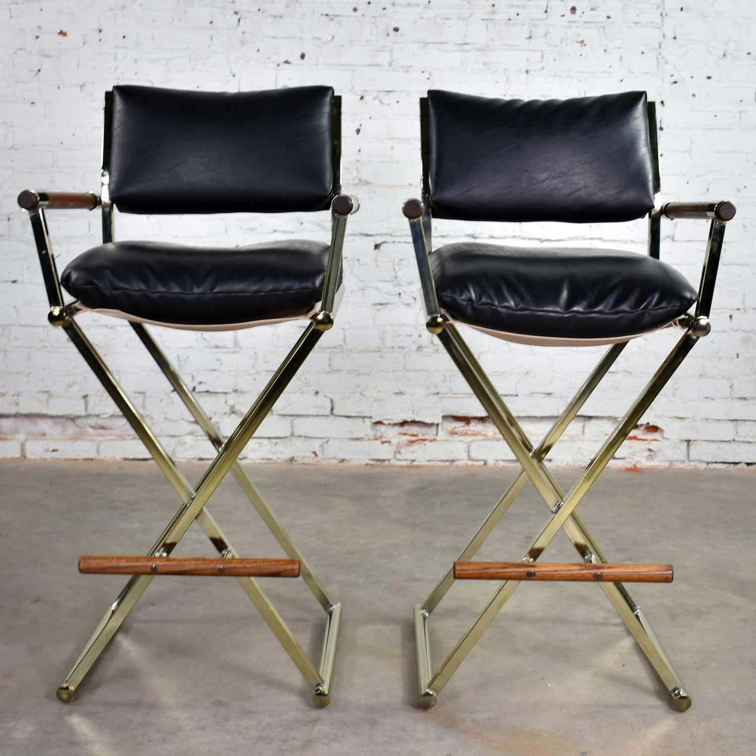 Handsome pair of vintage director’s chair style barstools in brass plate, oak, and black vinyl. Some say in the style of Milo Baughman. They are in wonderful vintage condition with normal age appropriate wear but nothing outstanding. Please see
