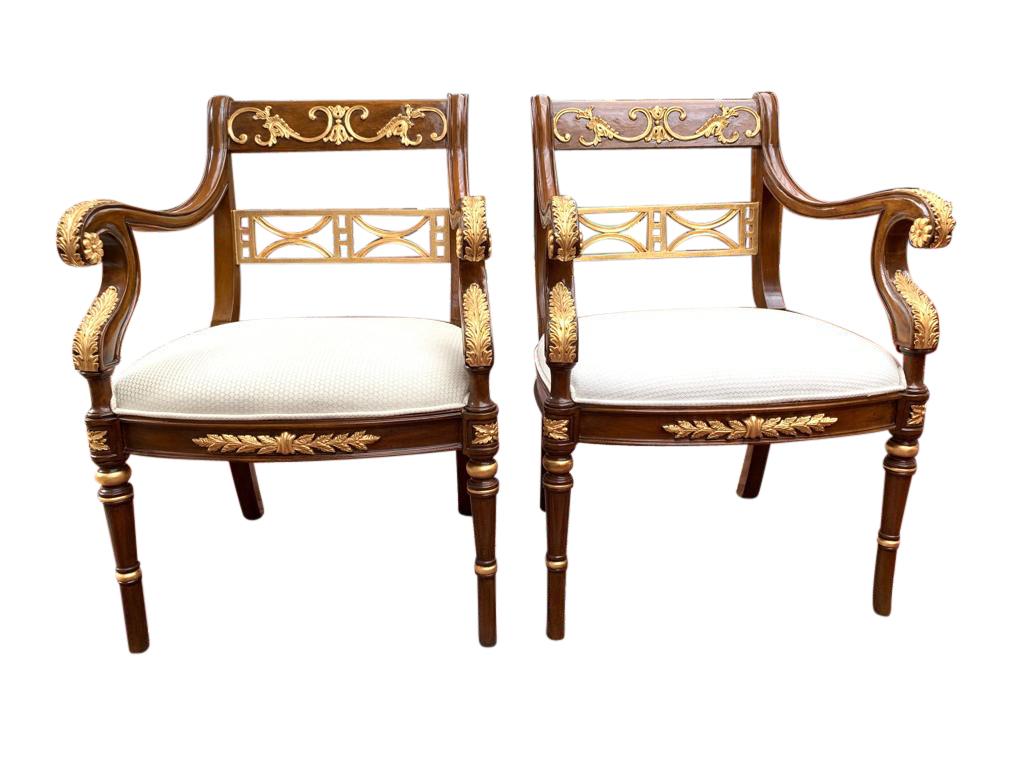 This is a beautiful vintage pair of Empire Revival mahogany and giltwood armchairs, late 20th century in date. The mahogany is beautiful in color and has been embellished with striking gilded high-lights in the form of acathus leaves and c scrolls.