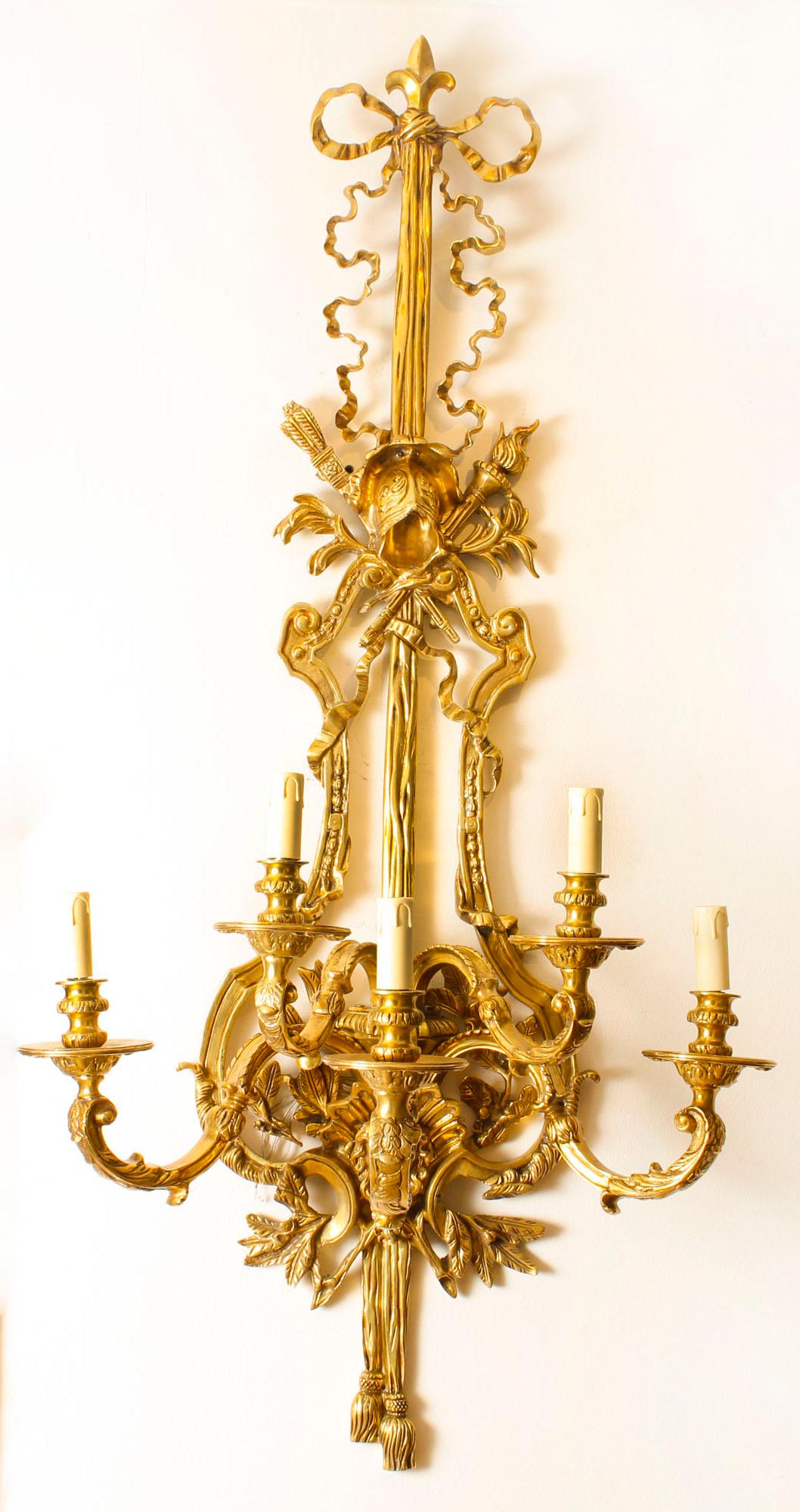 This is a stunning monumental vintage pair of French Empire Revival ormolu wall lights, dating from the late 20th century.

They are beautifully decorated with bows, ribbons, flaming torches, tassels, etc.
and each has five lights. 

The