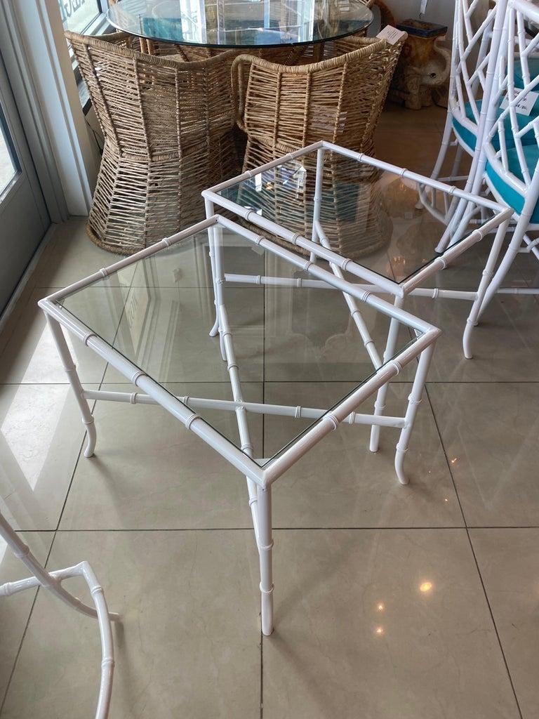 Vintage pair of metal, faux bamboo indoor outdoor side end tables. These have been newly powder-coated in white with new glass tops. Dimensions: 21 H x 20.5 W x 26.5 D.