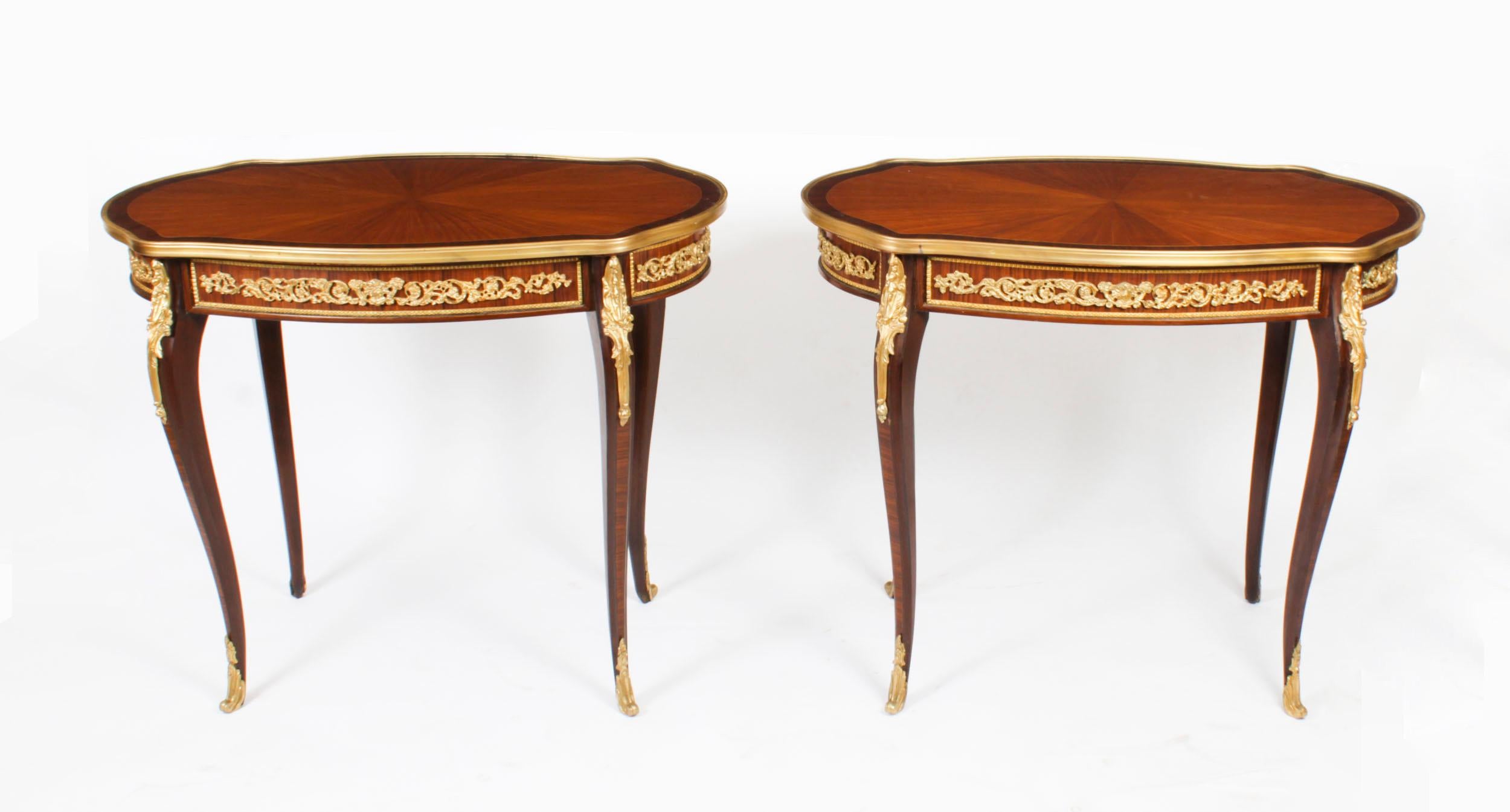 This is a beautiful pair of vintage French Louis Revival ormolu mounted side tables, Mid-20th Century in date.

The oval shaped tables are framed with decorative ormolu borders and the tops feature satinwood starbursts with crossbanded borders.