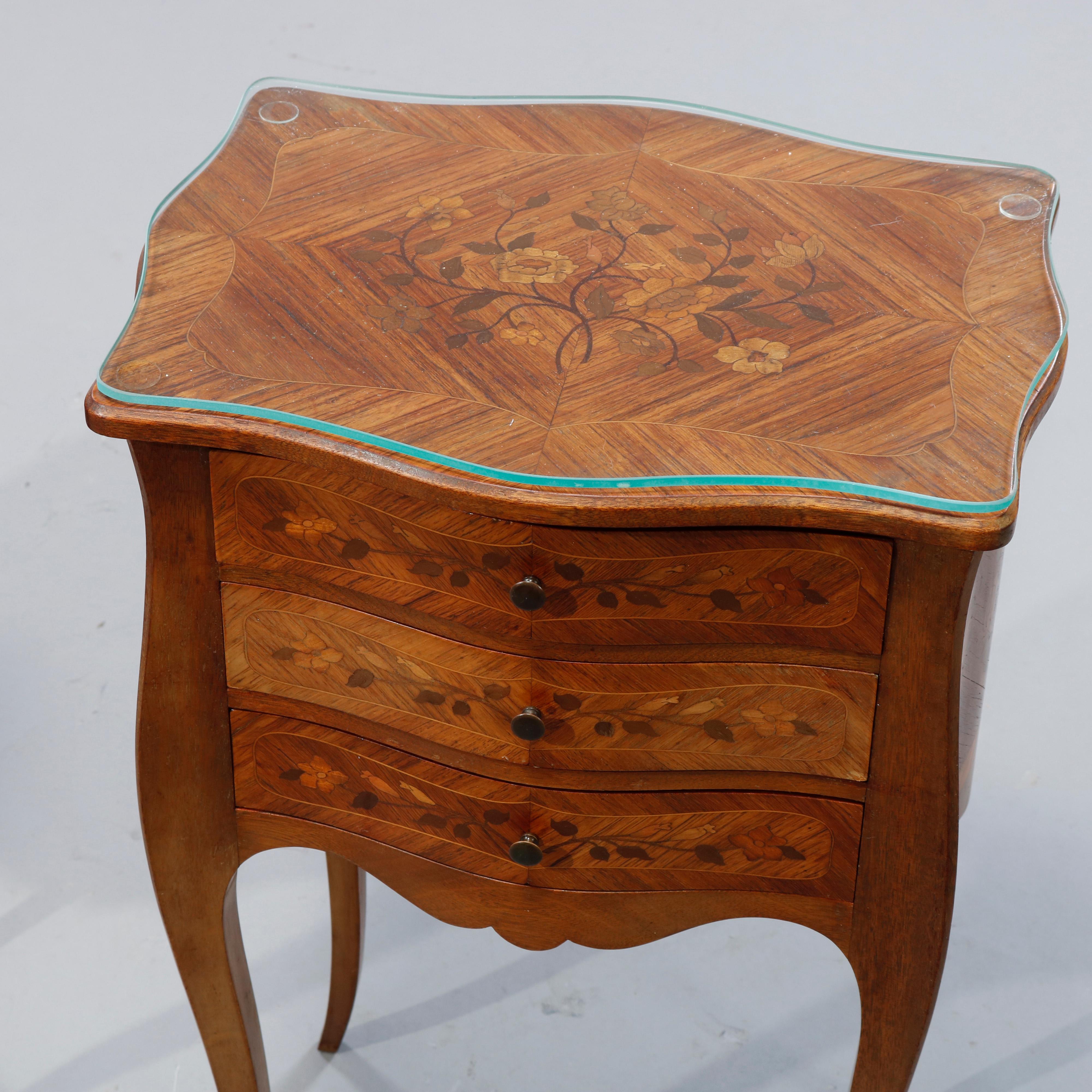 An vintage pair of French side stands offer mahogany construction in serpentine form with bookmatched facing and inlaid satinwood floral marquetry having shaped tops over three drawer case raised on tapered cabriole legs, c1930.

Measures: 22.25