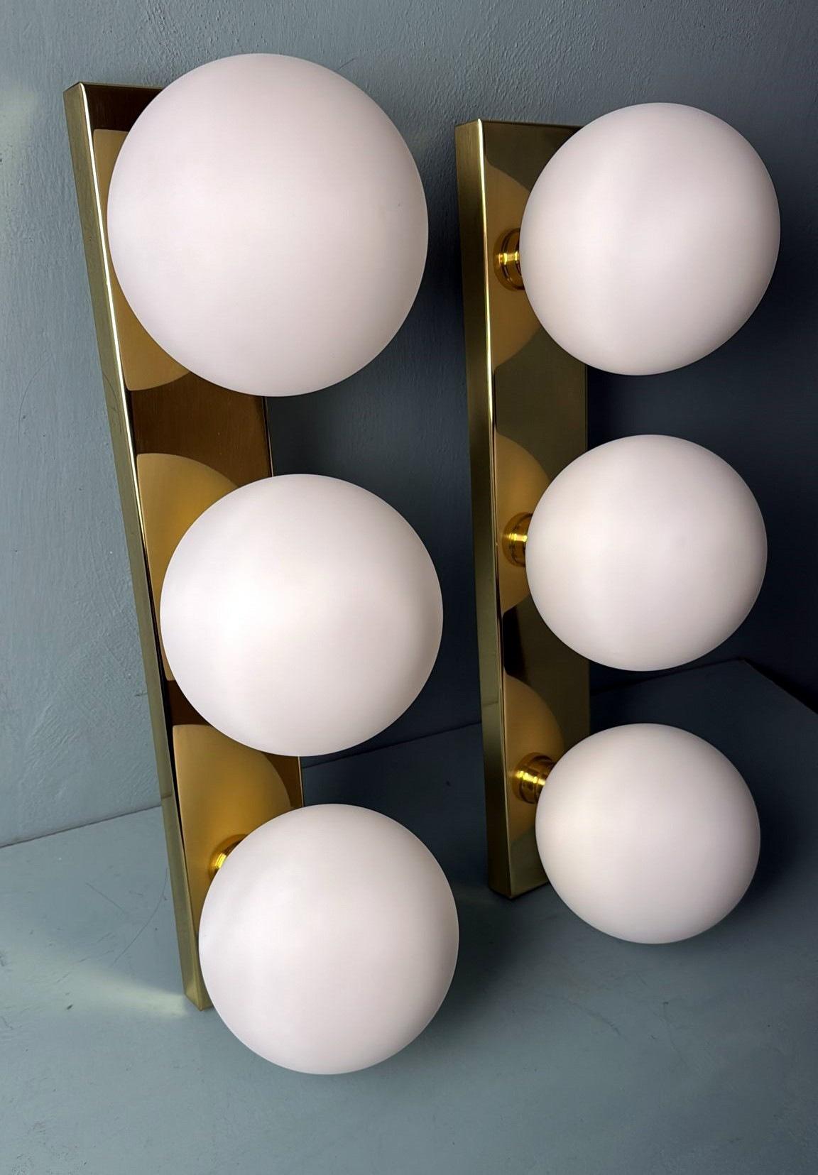Veuillez lire attentivement cette description, car elle contient des informations techniques et historiques détaillées qui garantissent l'authenticité de nos articles.
Cette élégante paire d'appliques murales présente trois globes en verre opalin,