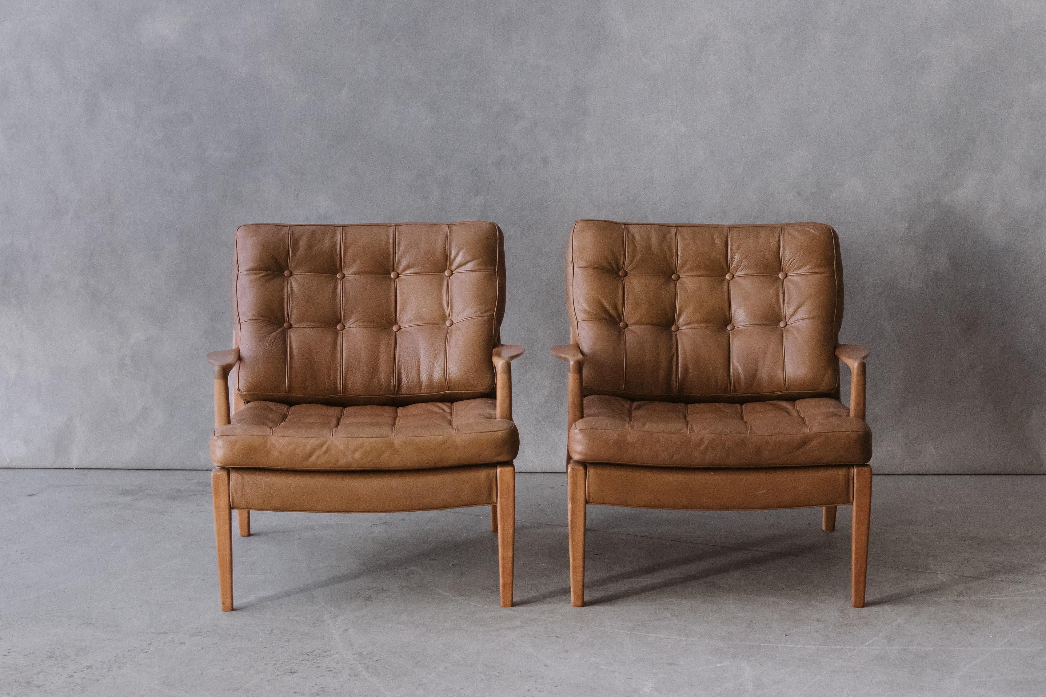 Vintage pair of Arne Norell lounge chairs, Model Merkur, Sweden 1970s. Solid birch frame construction with original tan leather cushions. Light wear and use.


