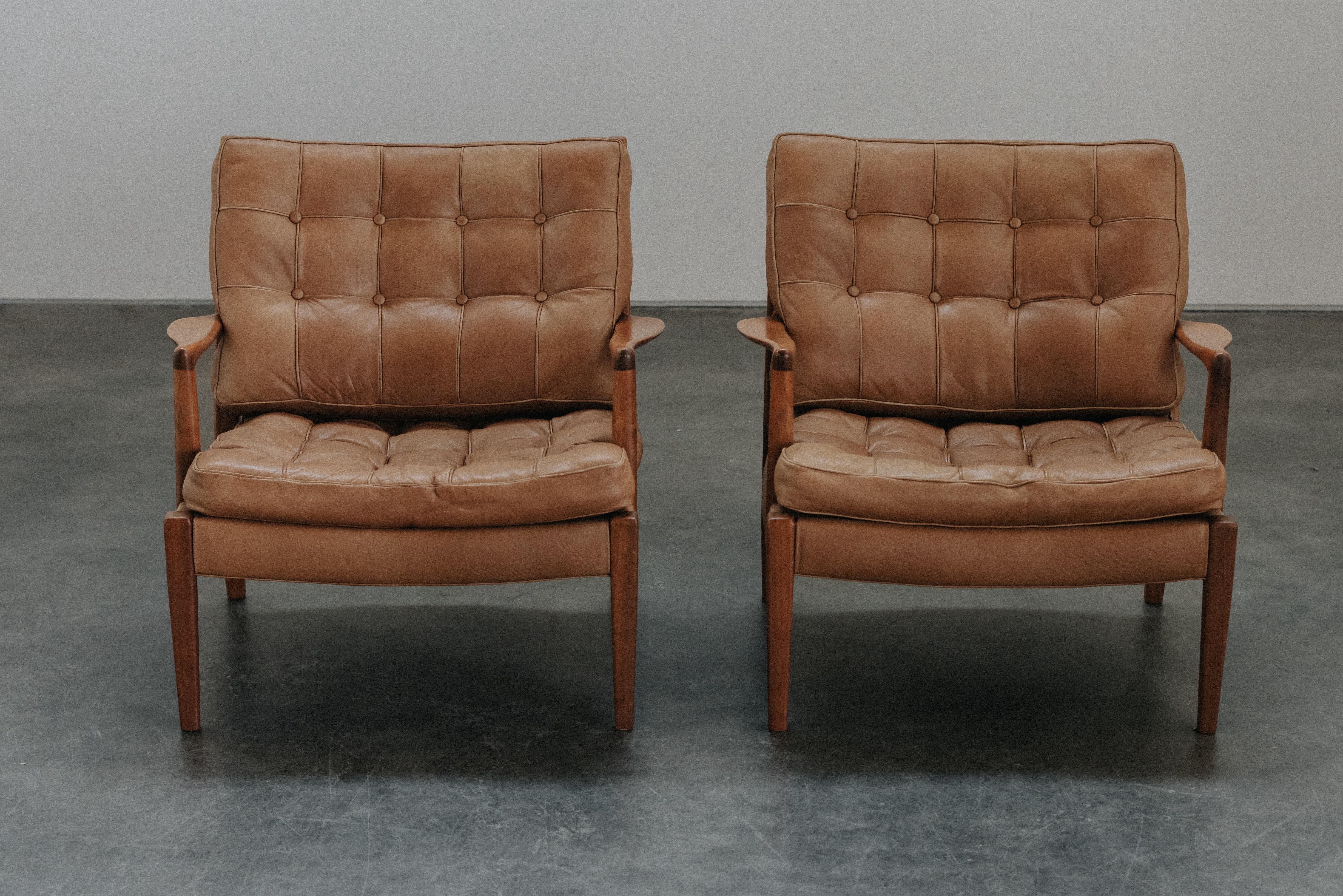 Vintage Pair Of Arne Norell Merkur Lounge Chairs From Sweden, Circa 1970.  Solid birch construction with original cognac leather cushions.  Great patina and use.
