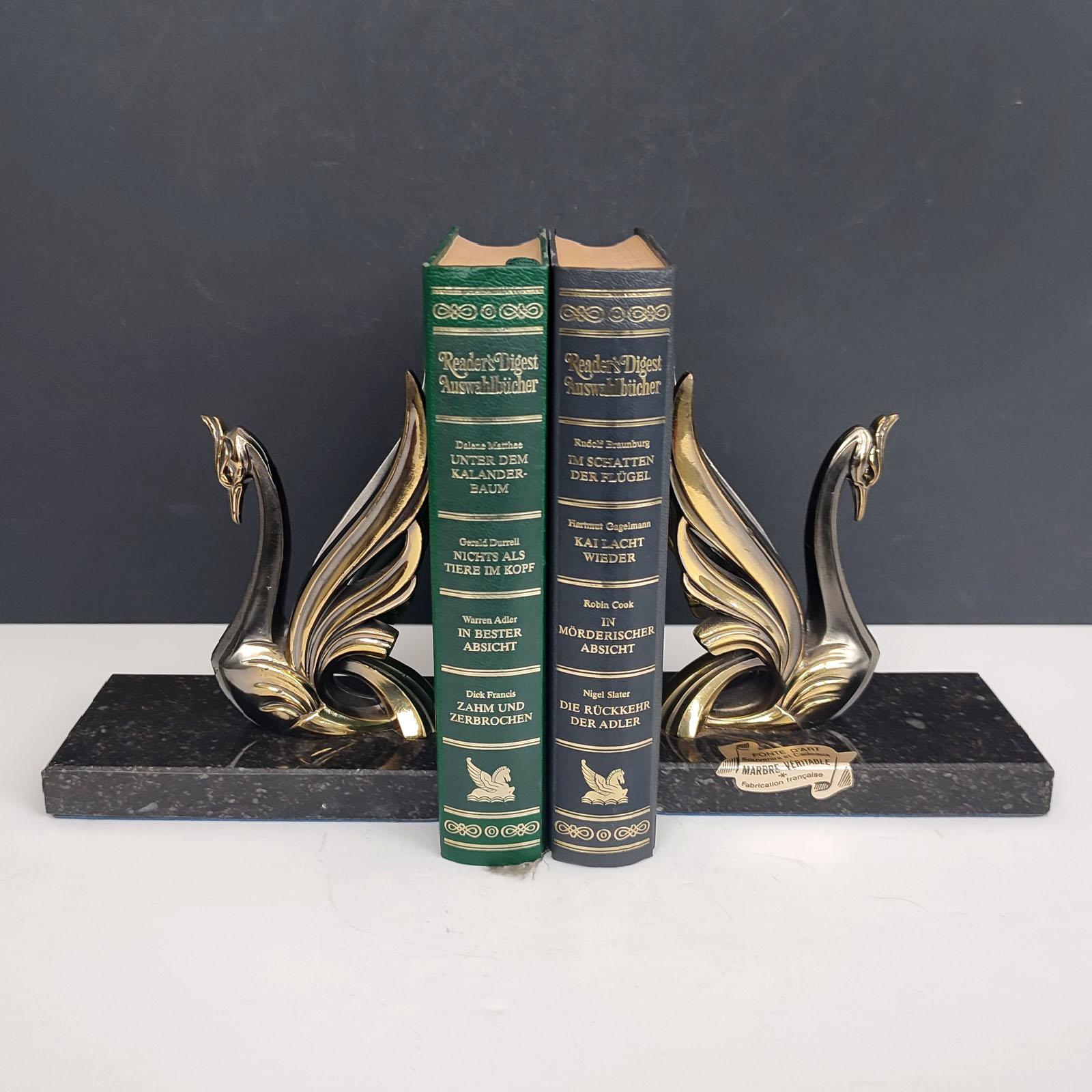 Pair of midcentury vintage cast metal polished decorative swan bookends on marble bases. 
Great for holding up books on a bookshelf or as paper weights on a desk or decorative heavy birds animal sculptures around the house.
This stunning vintage