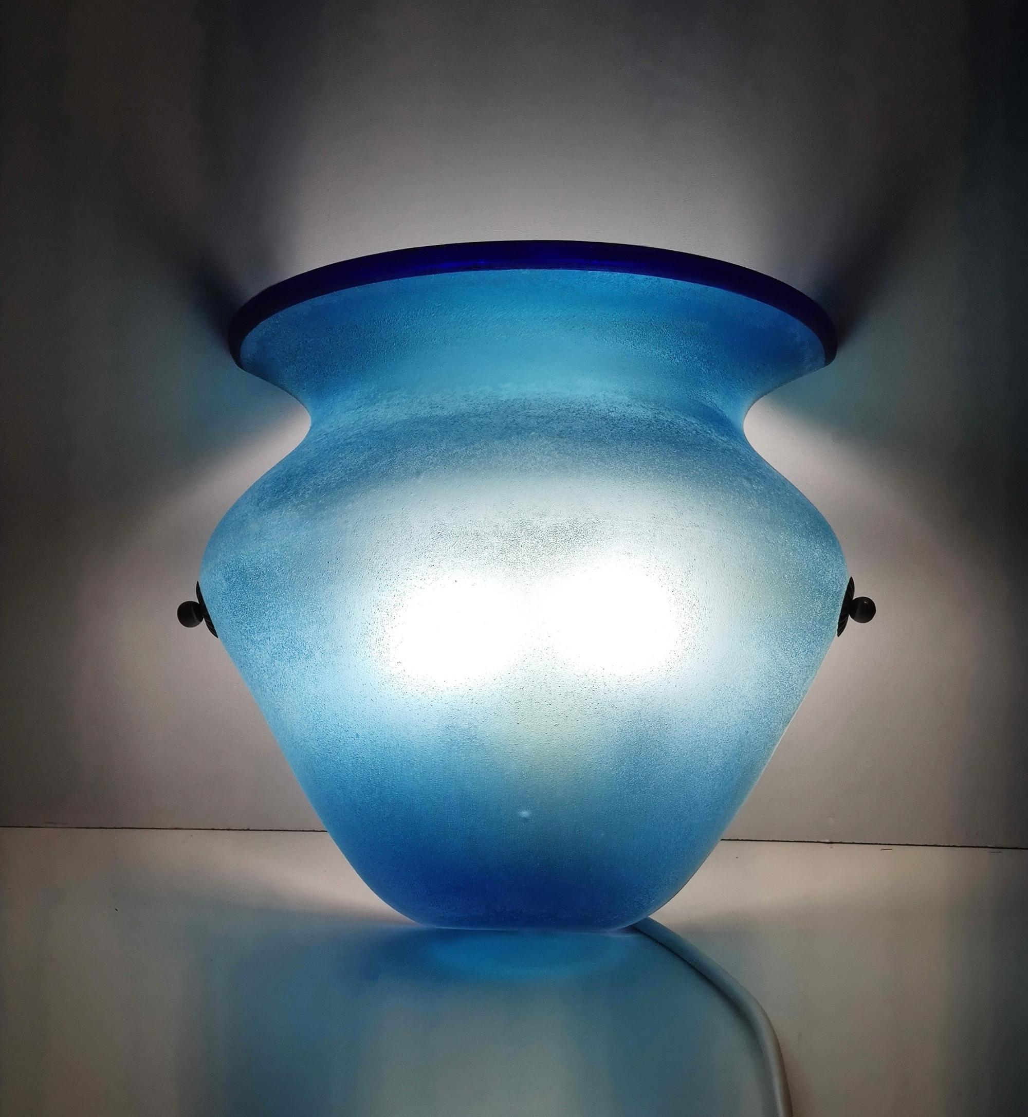 Made in Italy, 1960s. 
They are made in blown and etched azure Murano glass with a scavo effect, attributable to Gino Cenedese.
These are vintage wall lights, therefore they might show slight traces of use, but they can be considered as in excellent